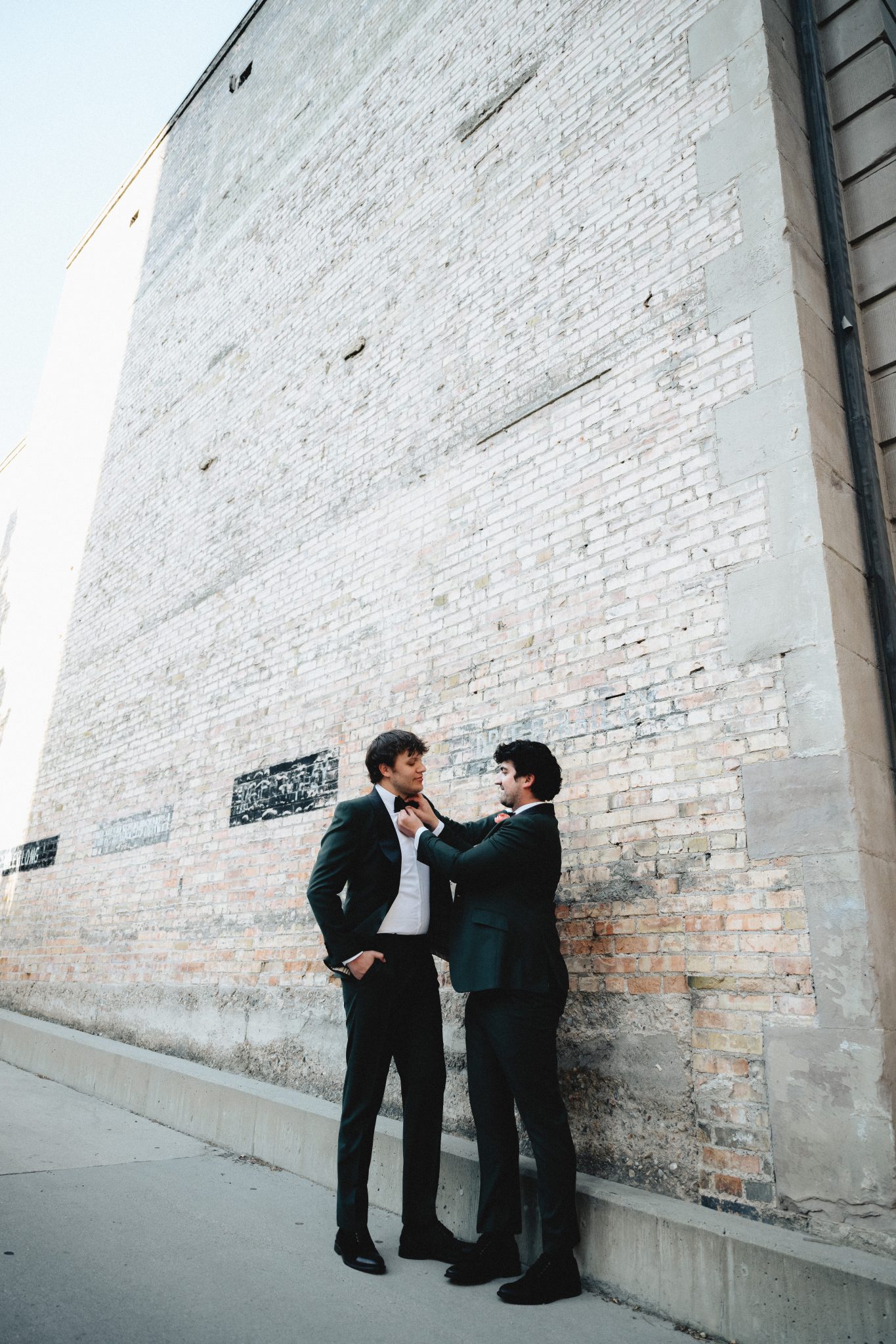 Grooms helping each other adjust their bowties outside a historic Salt Lake City venue - Salt Lake City Wedding Inspiration.