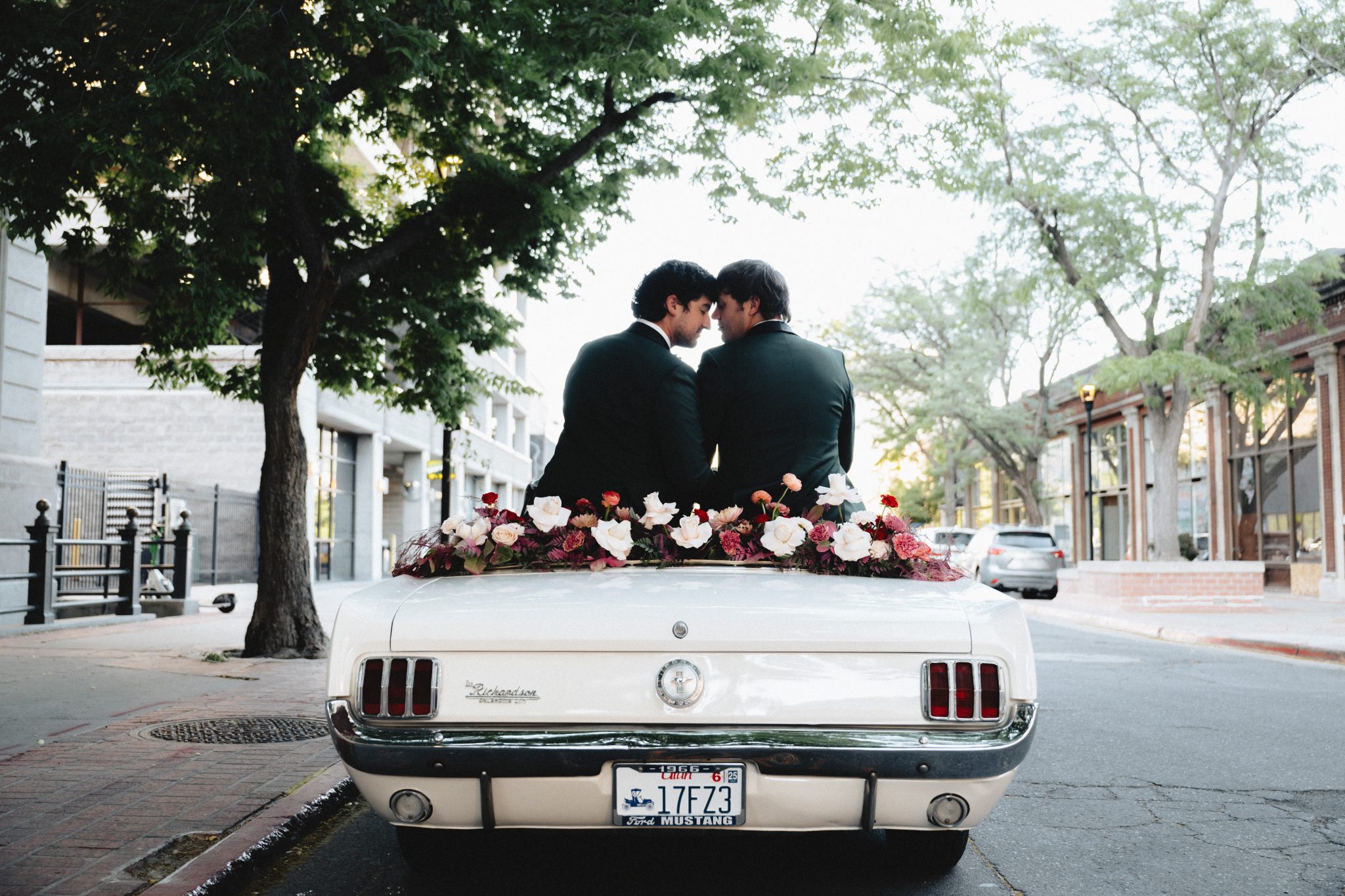 Newlywed couple sitting on the back of a white vintage car decorated with flowers in Salt Lake City - Salt Lake City Wedding Inspiration.