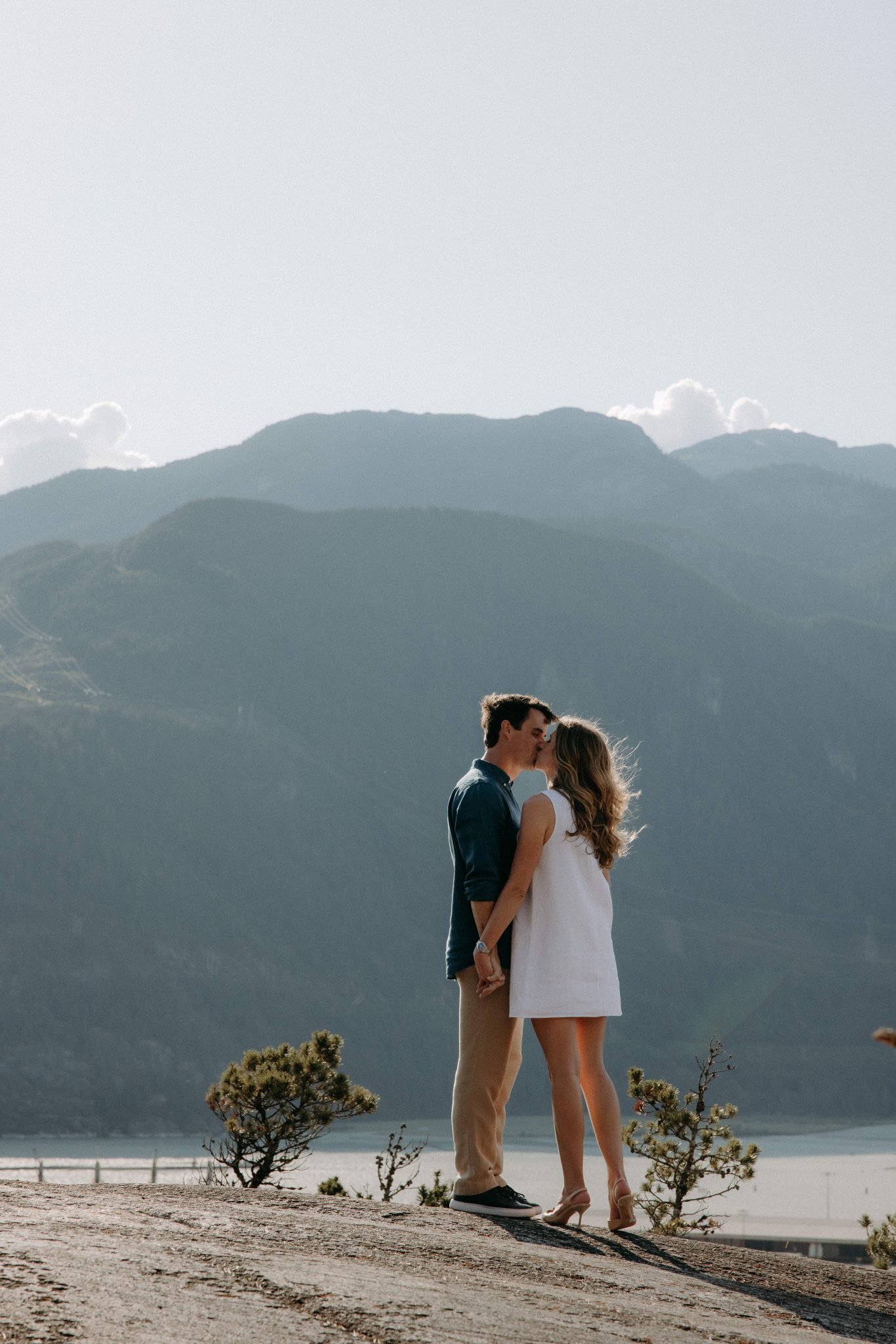 A couple sharing a kiss with the stunning mountains of British Columbia as their backdrop during their engagement shoot.
