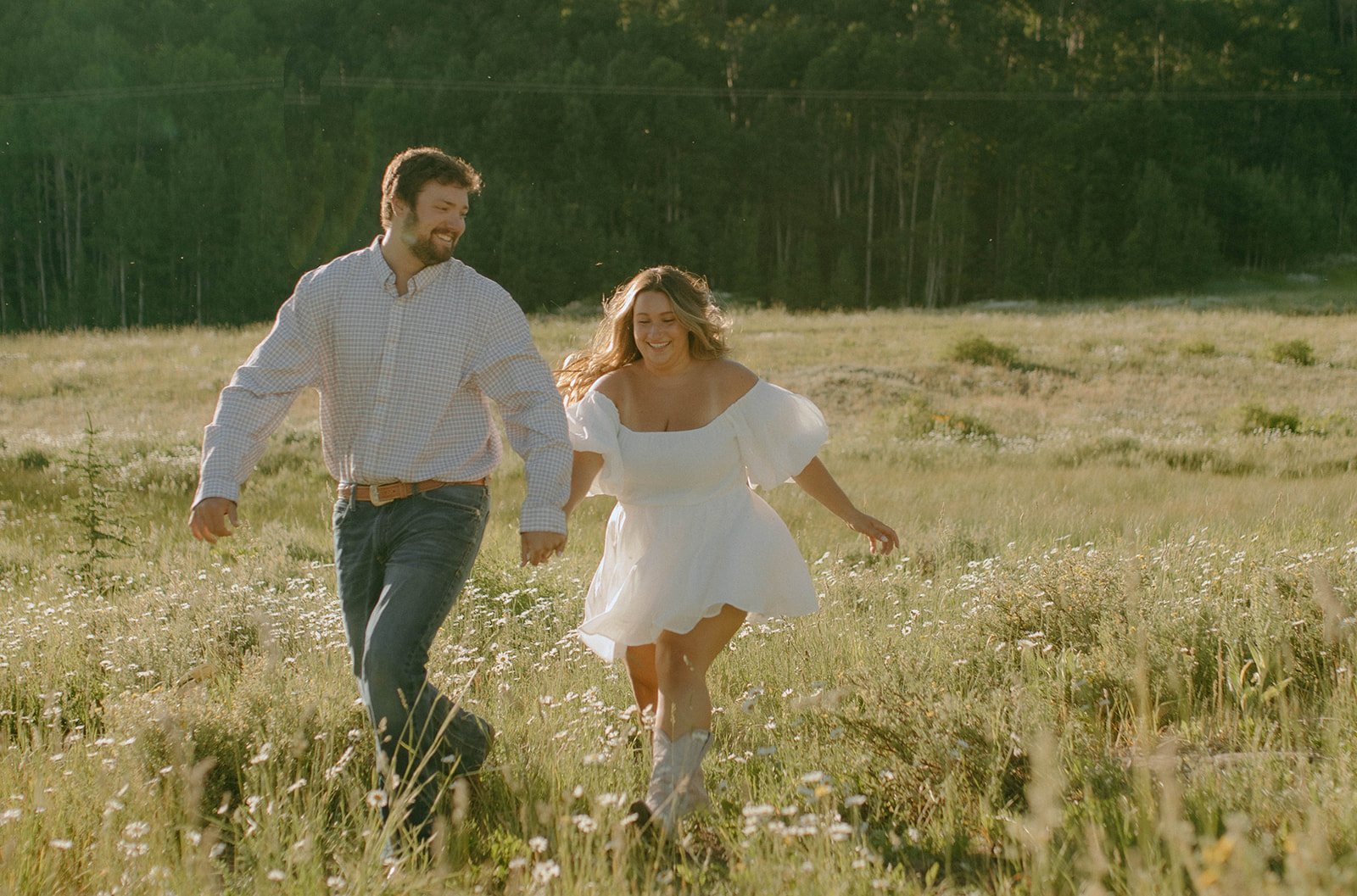 A loving couple sharing a playful embrace in a lush green field during their Durango engagement session.