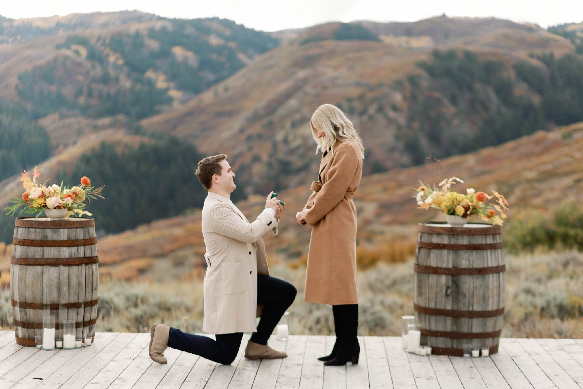 The groom-to-be on one knee during a surprise Park City proposal, set against a stunning mountainous landscape.