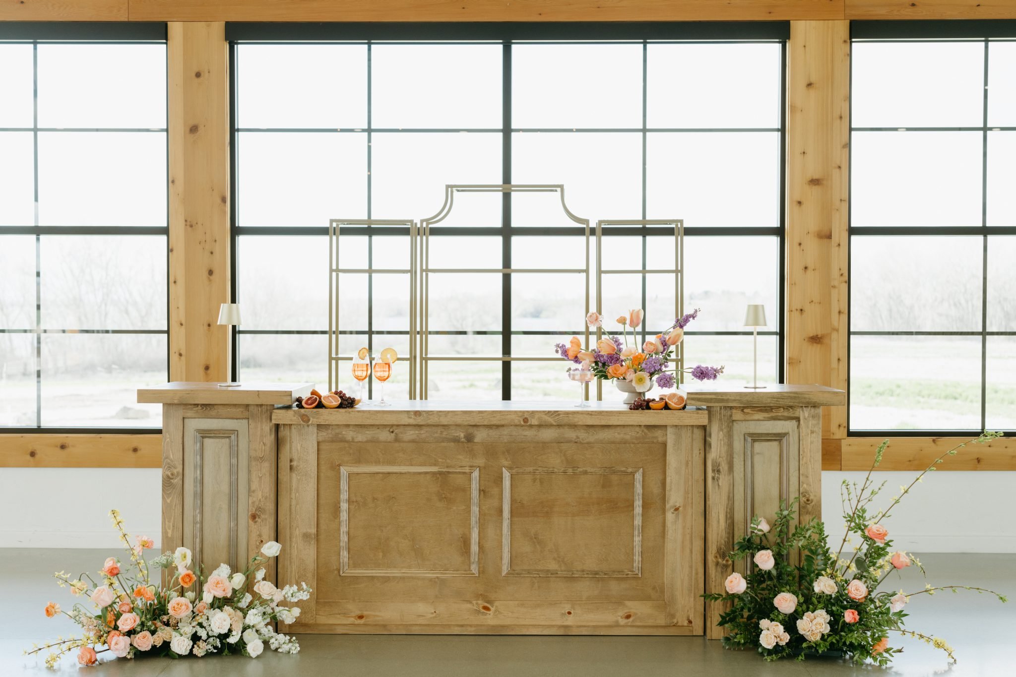 Stylish wooden bar adorned with spring flowers, serving cocktails at an indoor Idaho wedding reception.