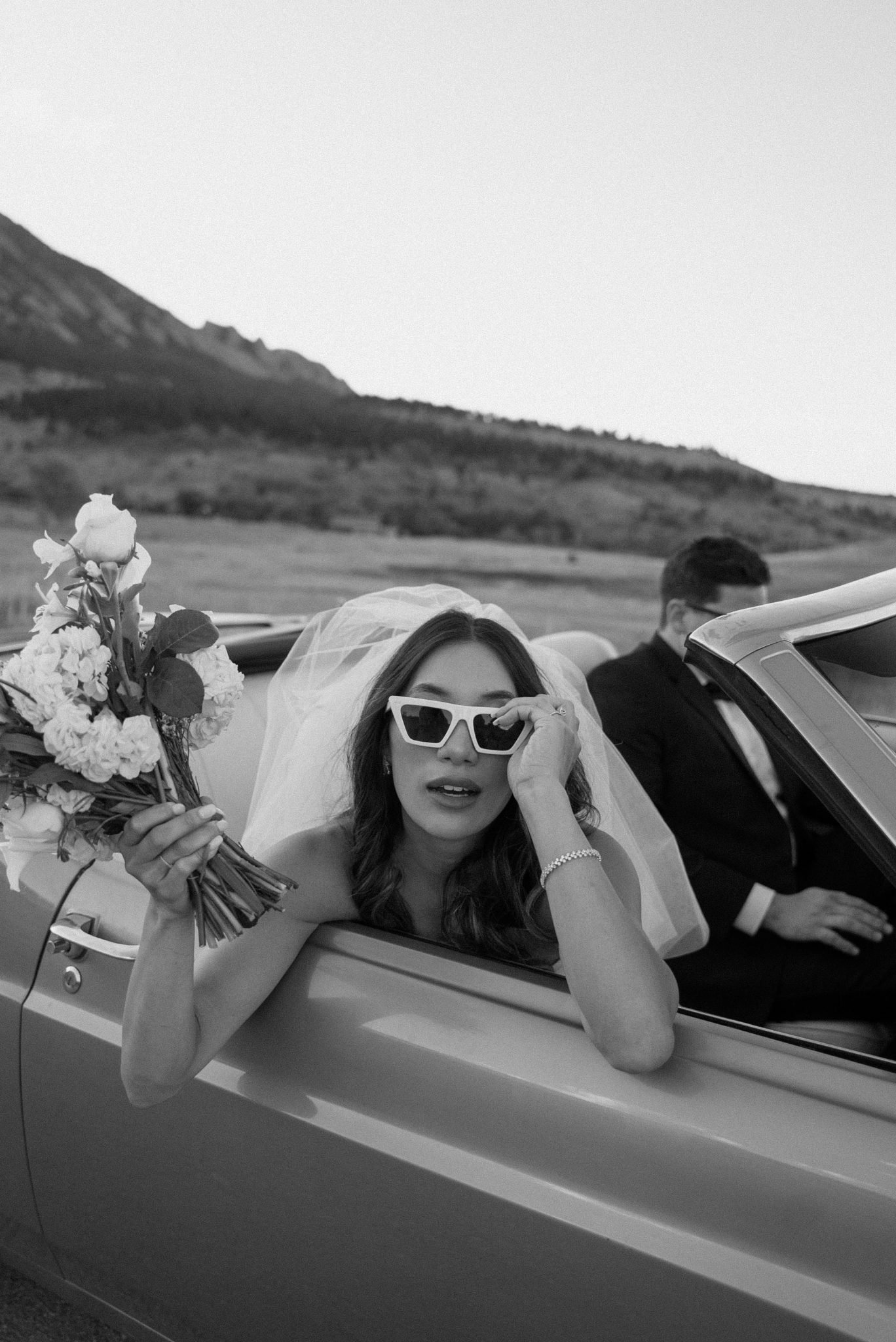 Bride-to-be wearing white sunglasses holding a bouquet during a Boulder engagement session.