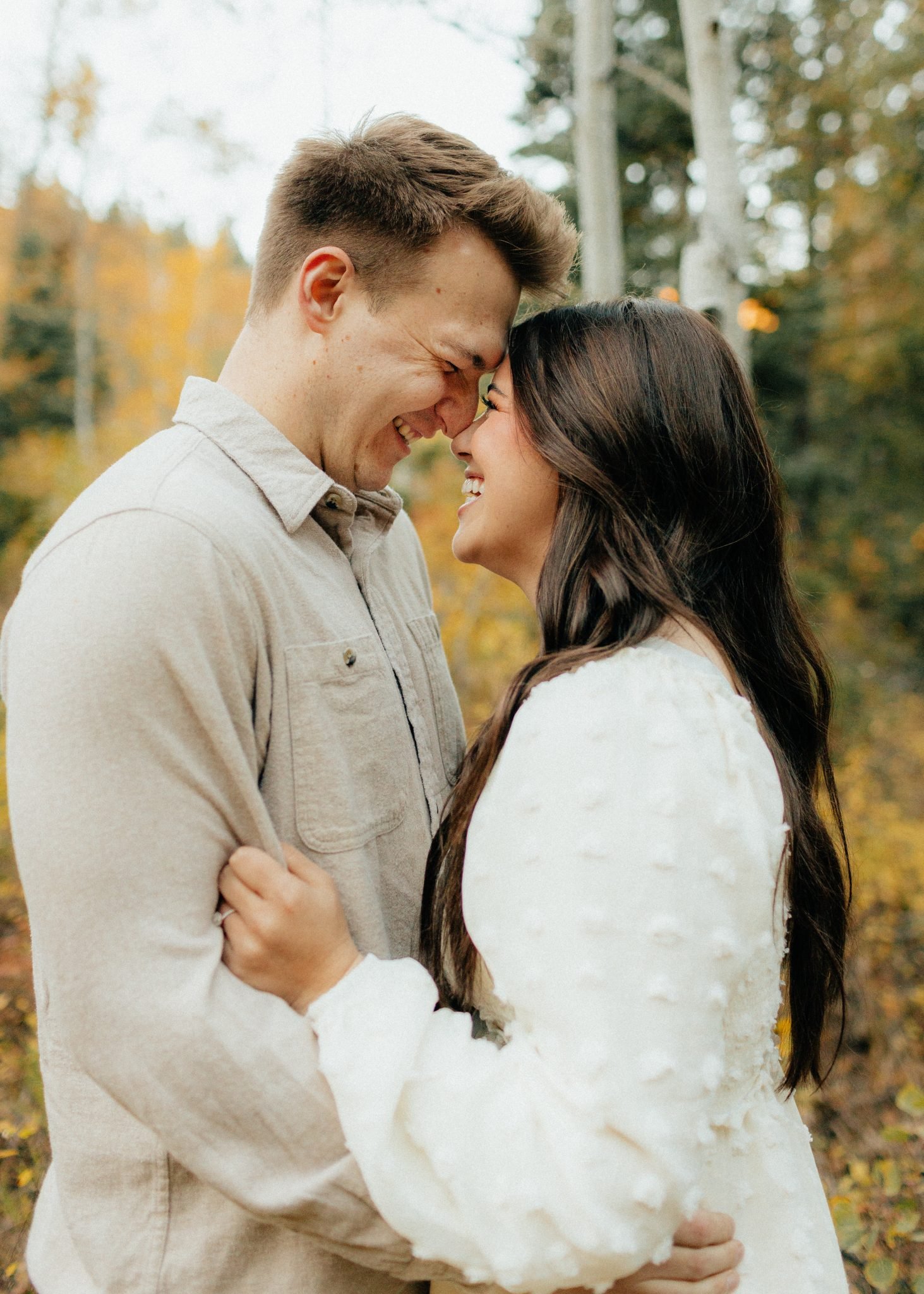 Couple sharing a joyful moment forehead-to-forehead during their fall Utah engagement.