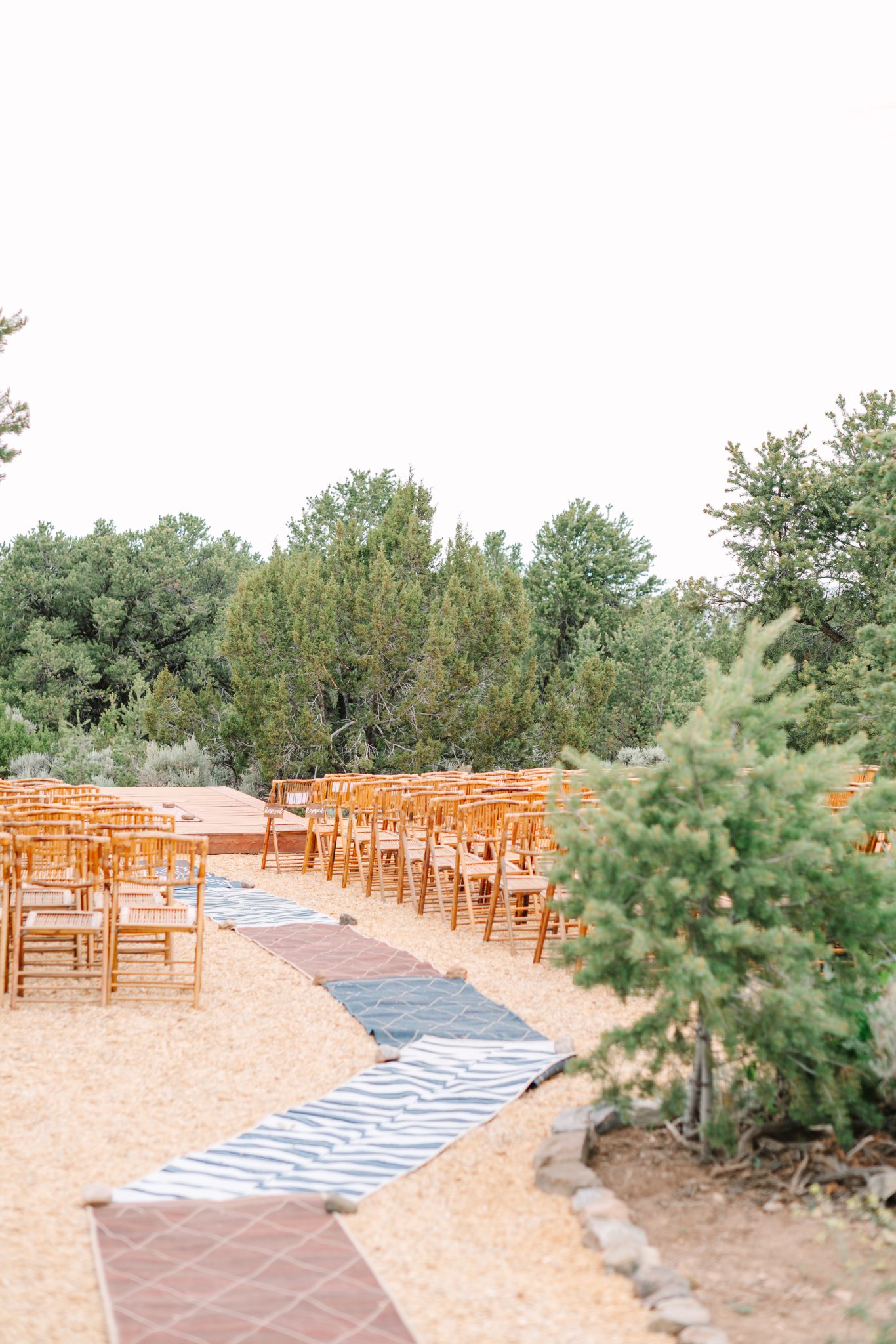Outdoor wedding ceremony setup with wooden chairs and natural desert scenery at a Taos wedding.
