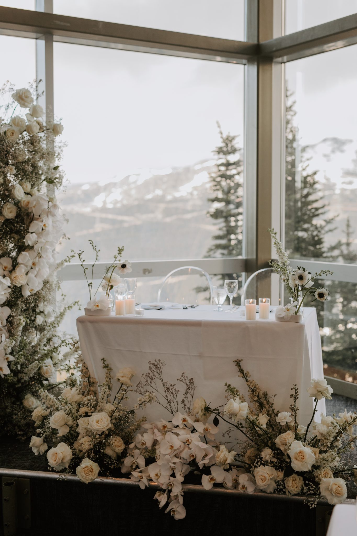 A beautifully styled sweetheart table adorned with white flowers, overlooking the majestic mountains of Whistler.