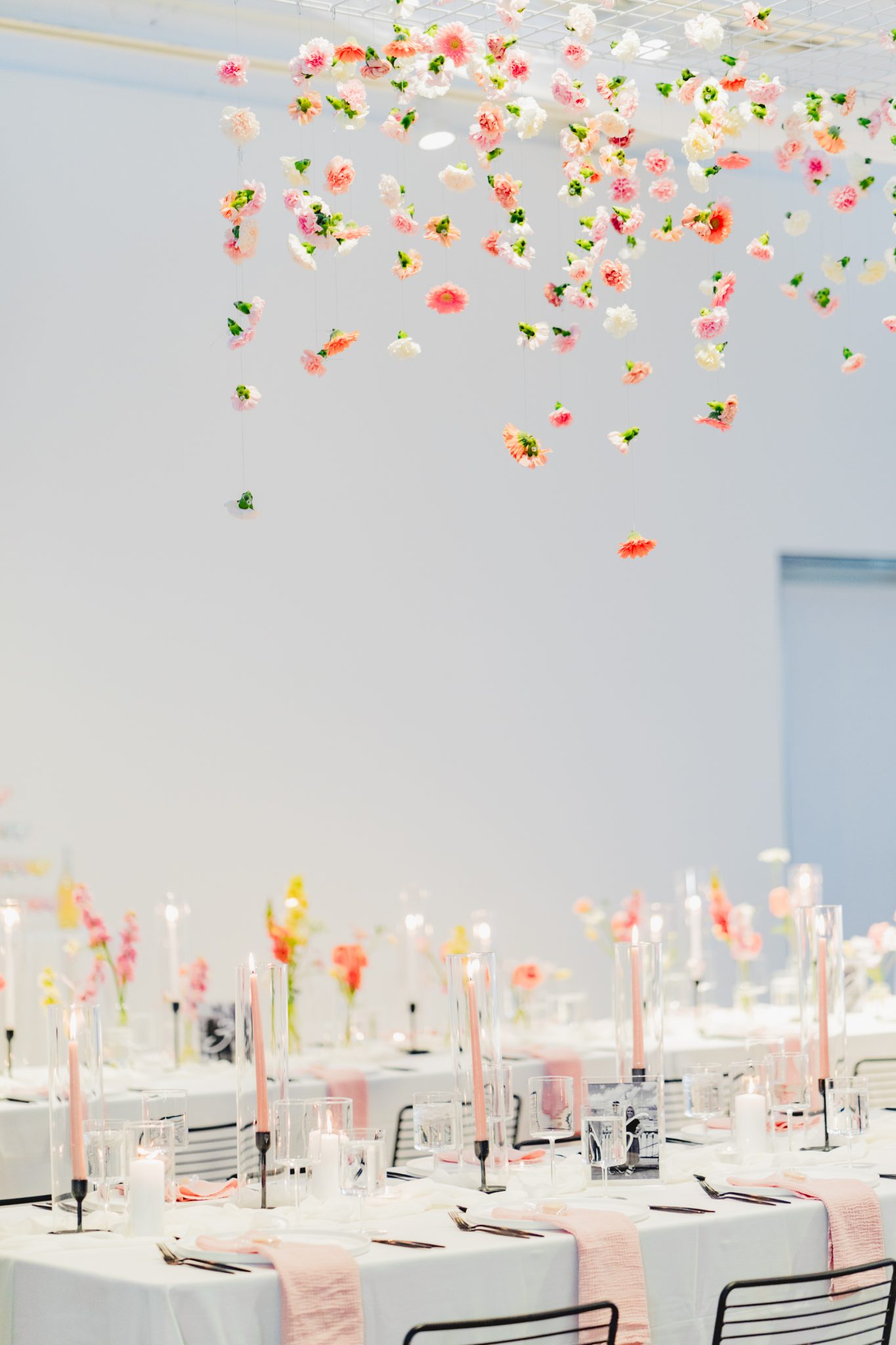 Elegant reception table settings with pink candles and floral centerpieces under hanging flowers at A Modern Floral Dream Wedding in Vancouver.
