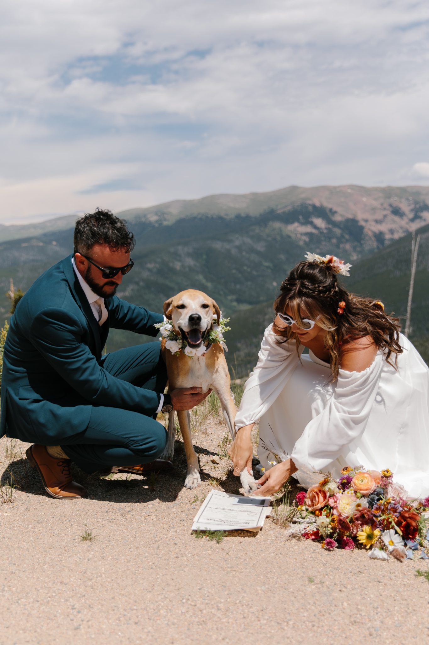 Bride and groom with their dog signing the marriage certificate outdoors at a Colorful Rustic Colorado Wedding.