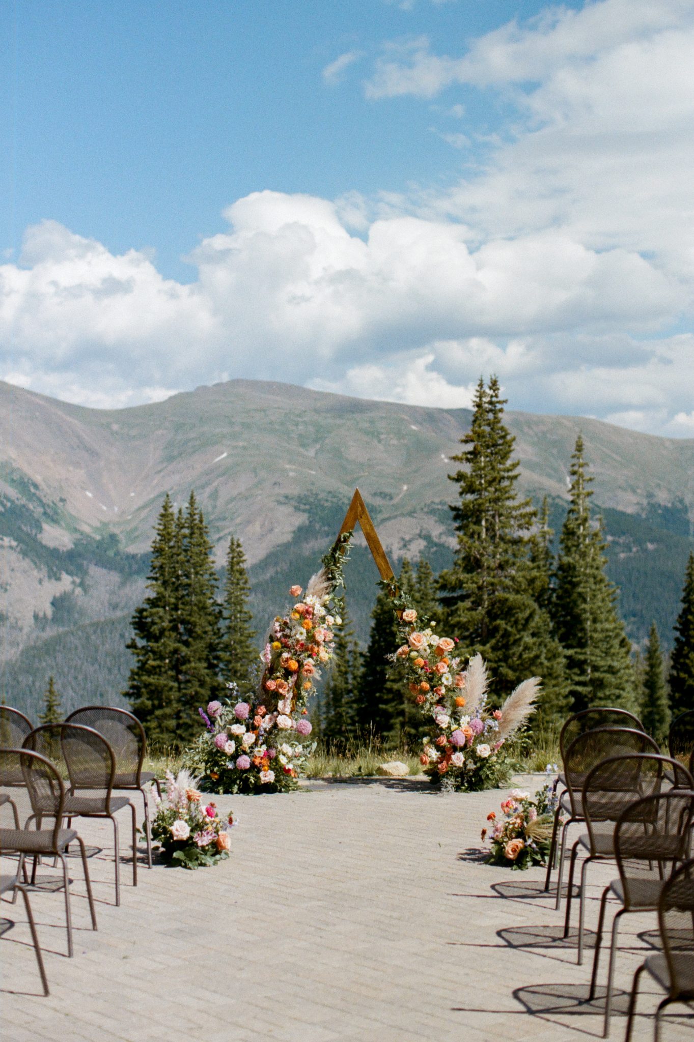 Outdoor wedding ceremony setup with a floral arch and mountain views at a Colorful Rustic Colorado Wedding.
