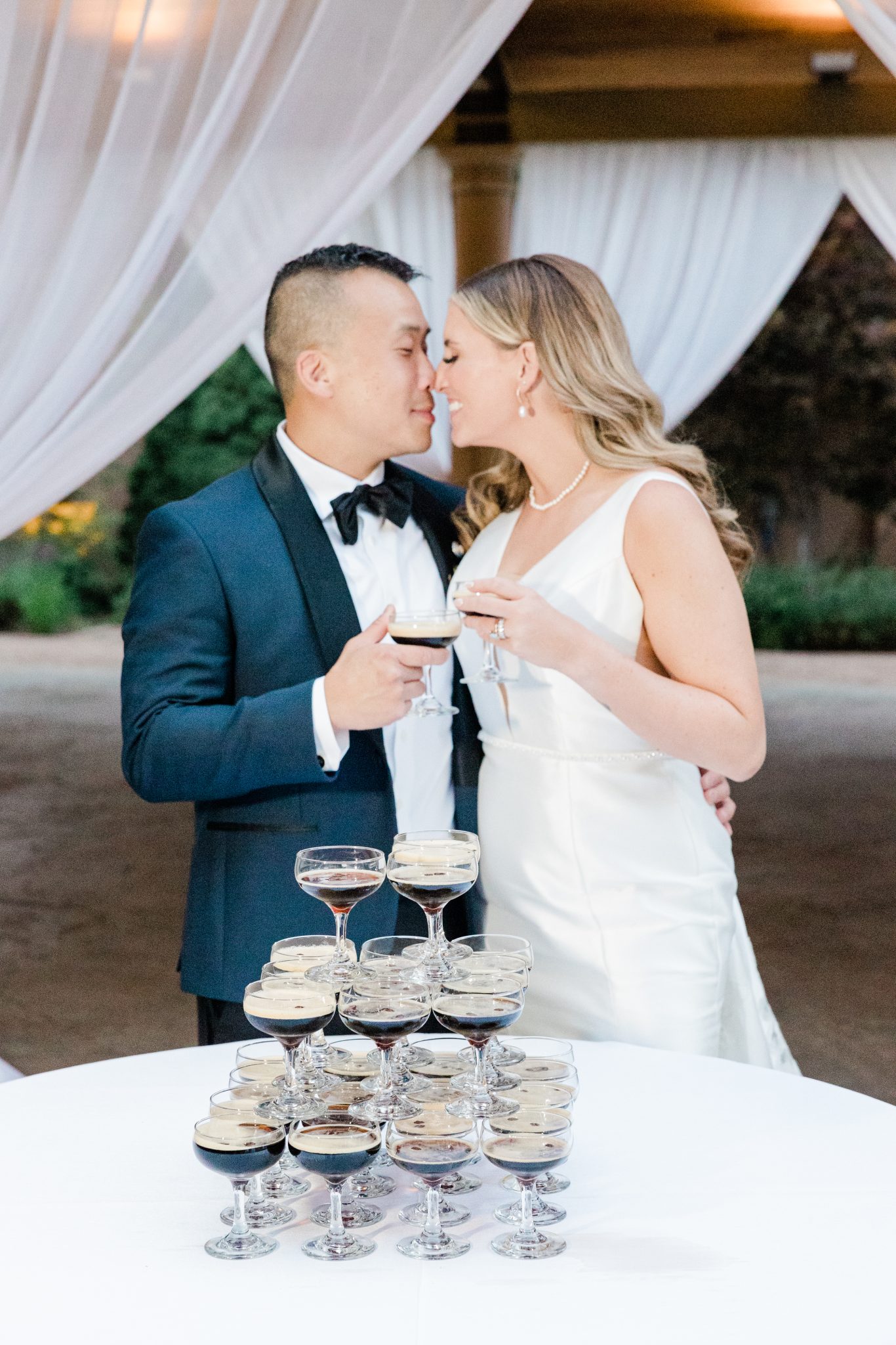 The bride and groom sharing a champagne toast, smiling at each other during The Broadmoor Chic Summer Wedding reception.