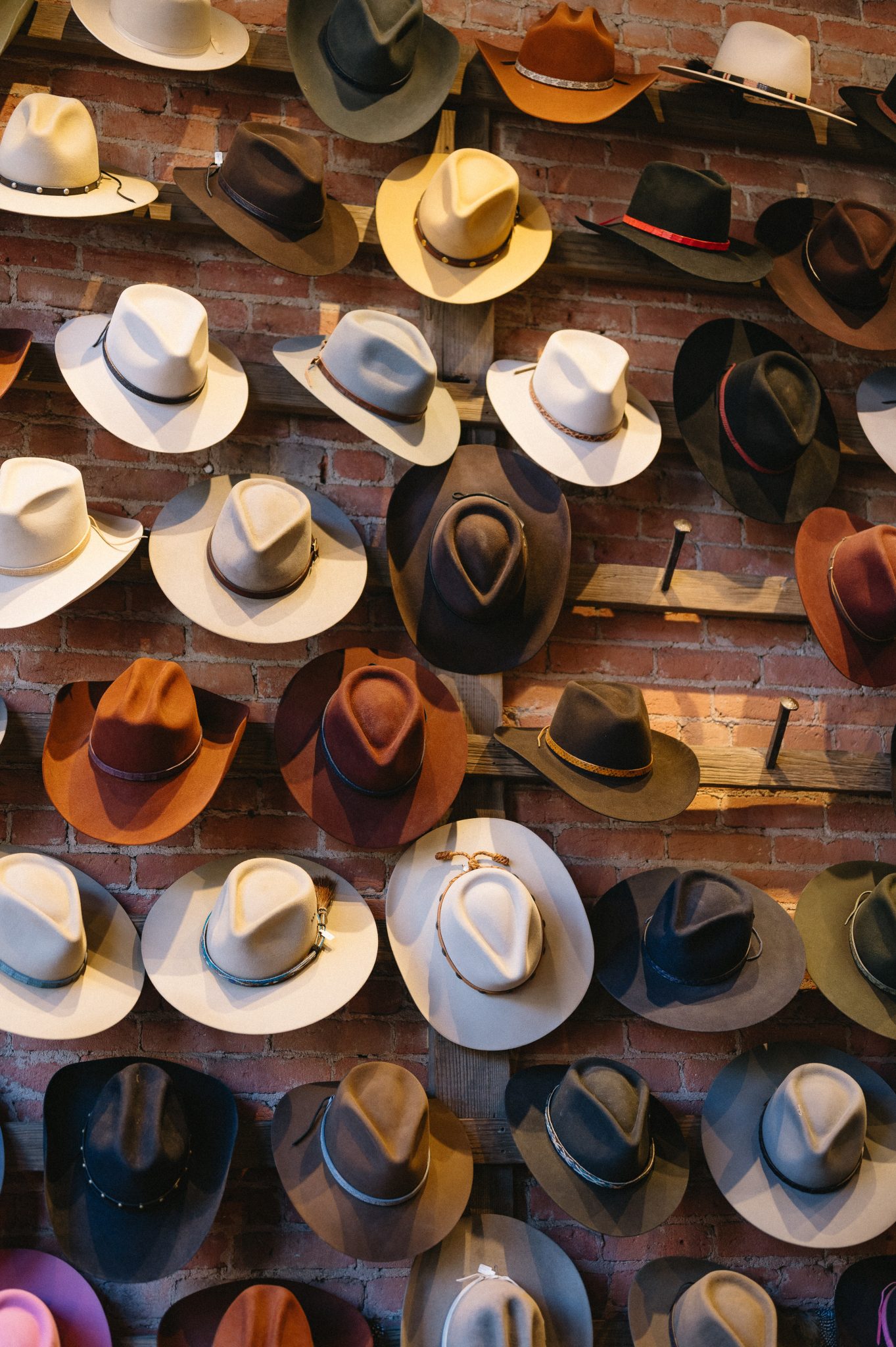 A wall full of stylish cowboy hats on display inside an Aspen boutique during a winter engagement session.
