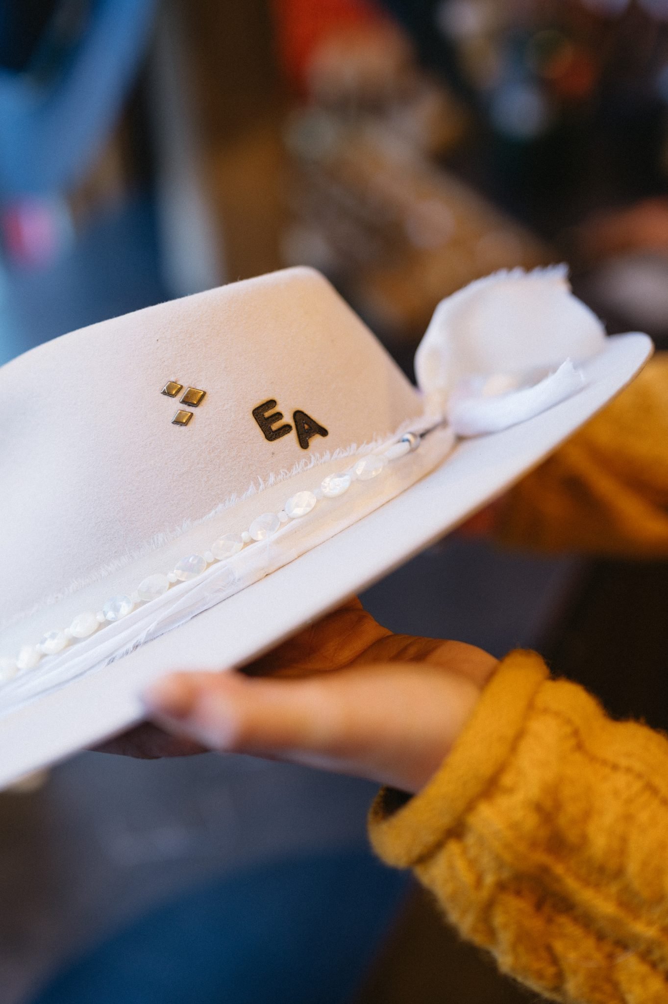 Close-up of a personalized white cowboy hat with custom initials during a winter engagement session in Aspen.