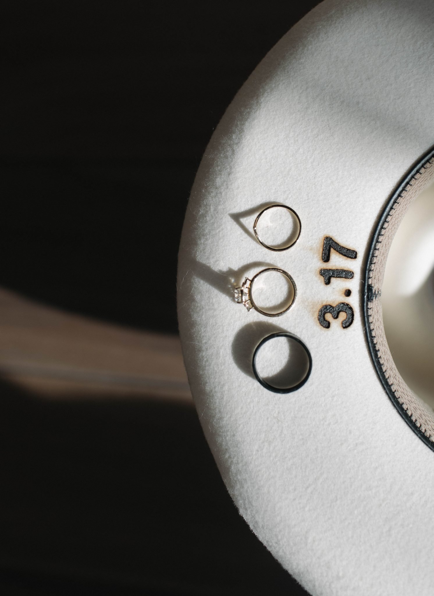 Wedding rings arranged on a white hat with a personalized date at a Fort Collins Colorado snowy elopement.
