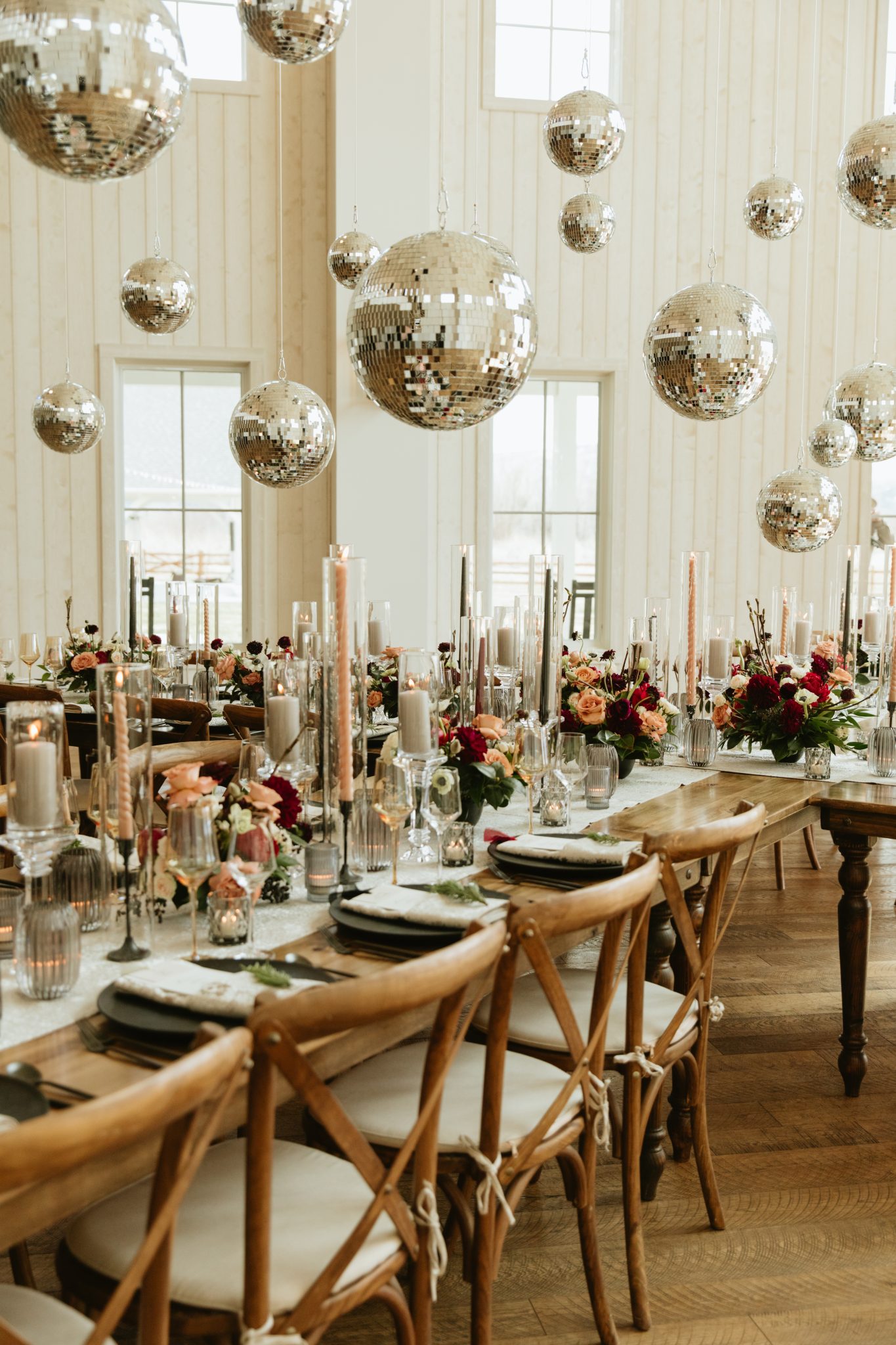 Elegant wedding reception setup with hanging disco balls and floral arrangements at River's Bottom Ranch during a winter snowy Utah wedding.