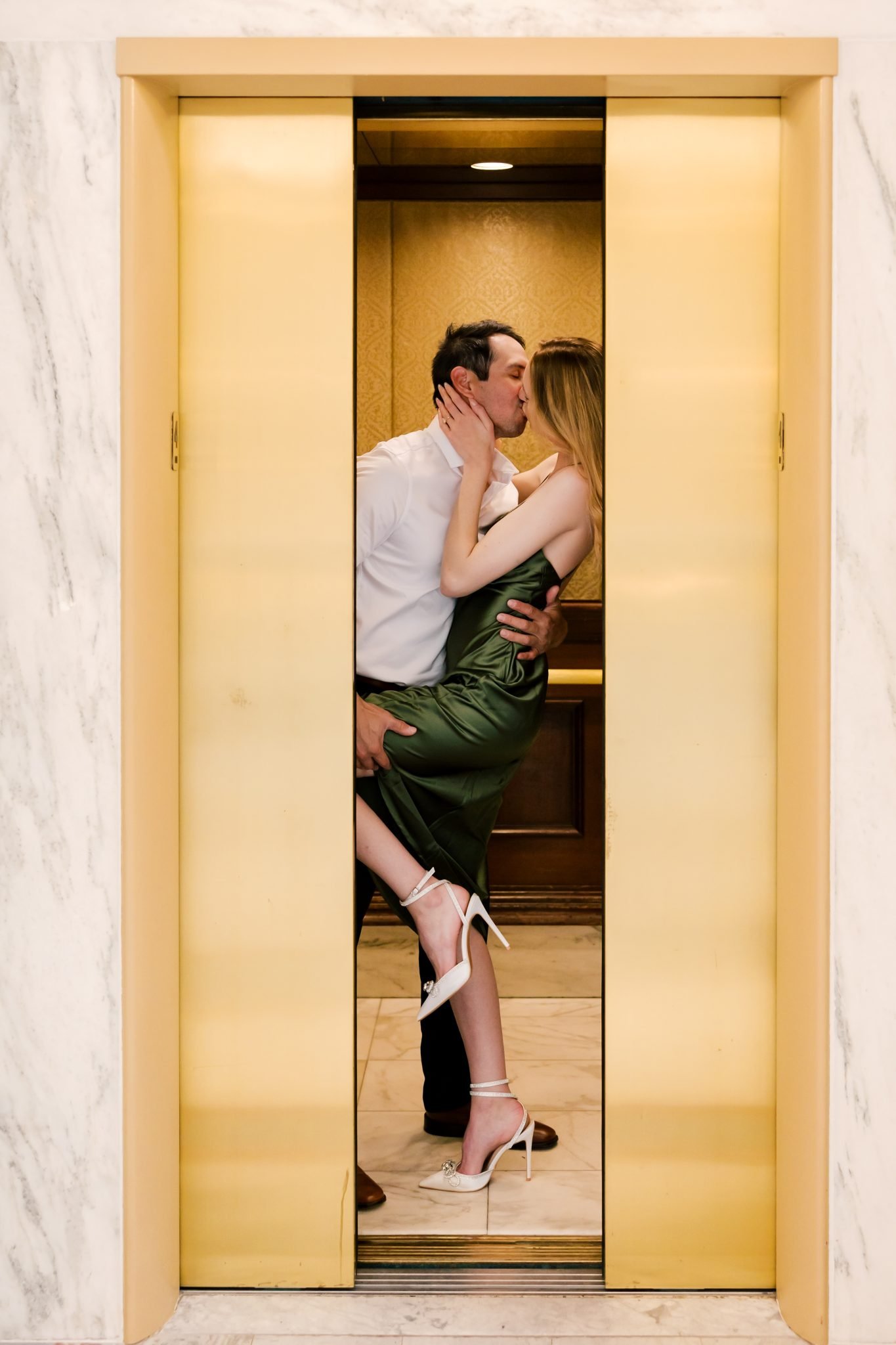 A couple captured mid-kiss in a golden elevator, highlighting the intimate and stylish nature of city engagements in Boise.