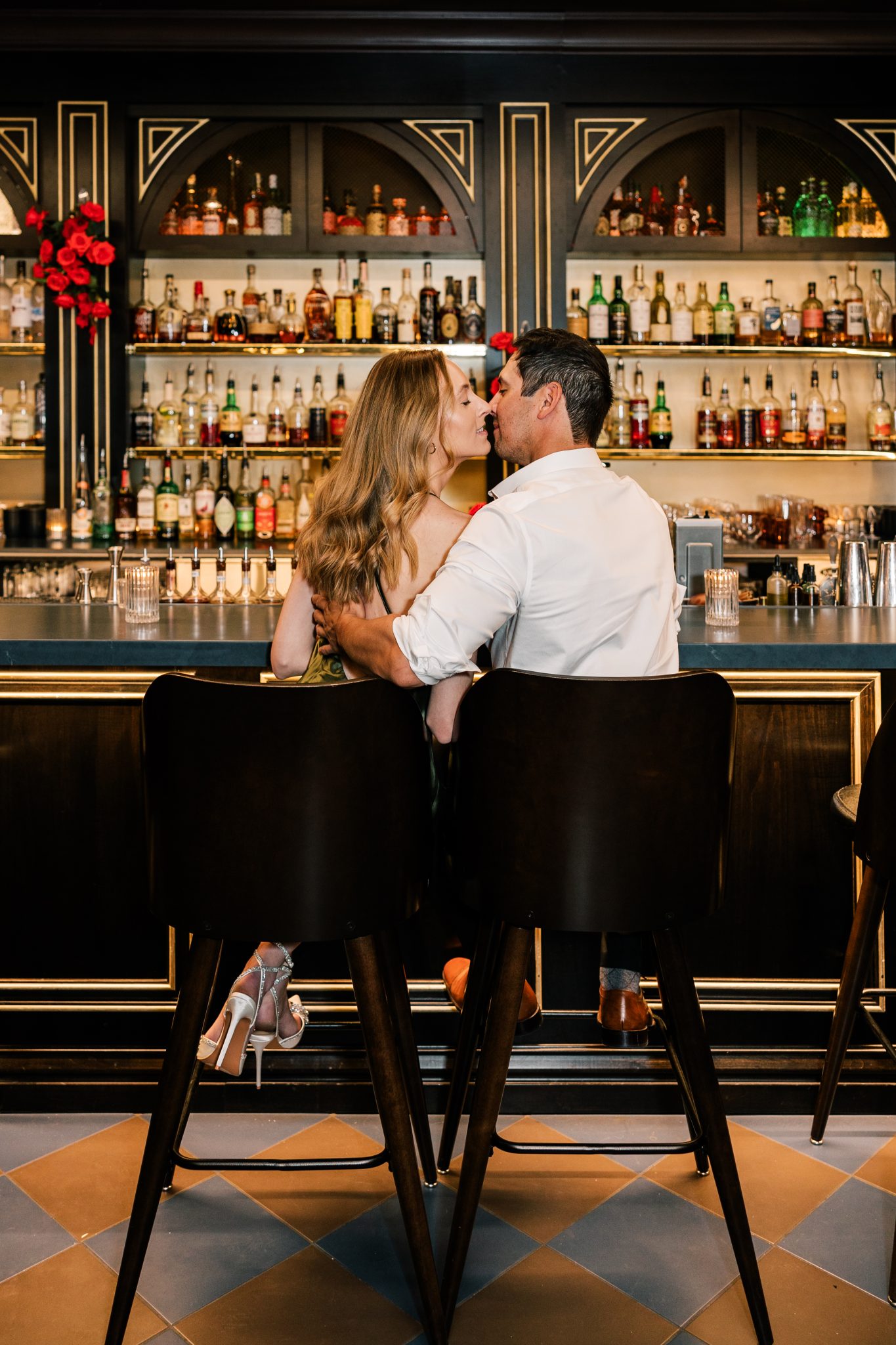A couple sharing a romantic moment at a chic bar, surrounded by elegant decor and vibrant lighting, showcasing city engagements in Boise.