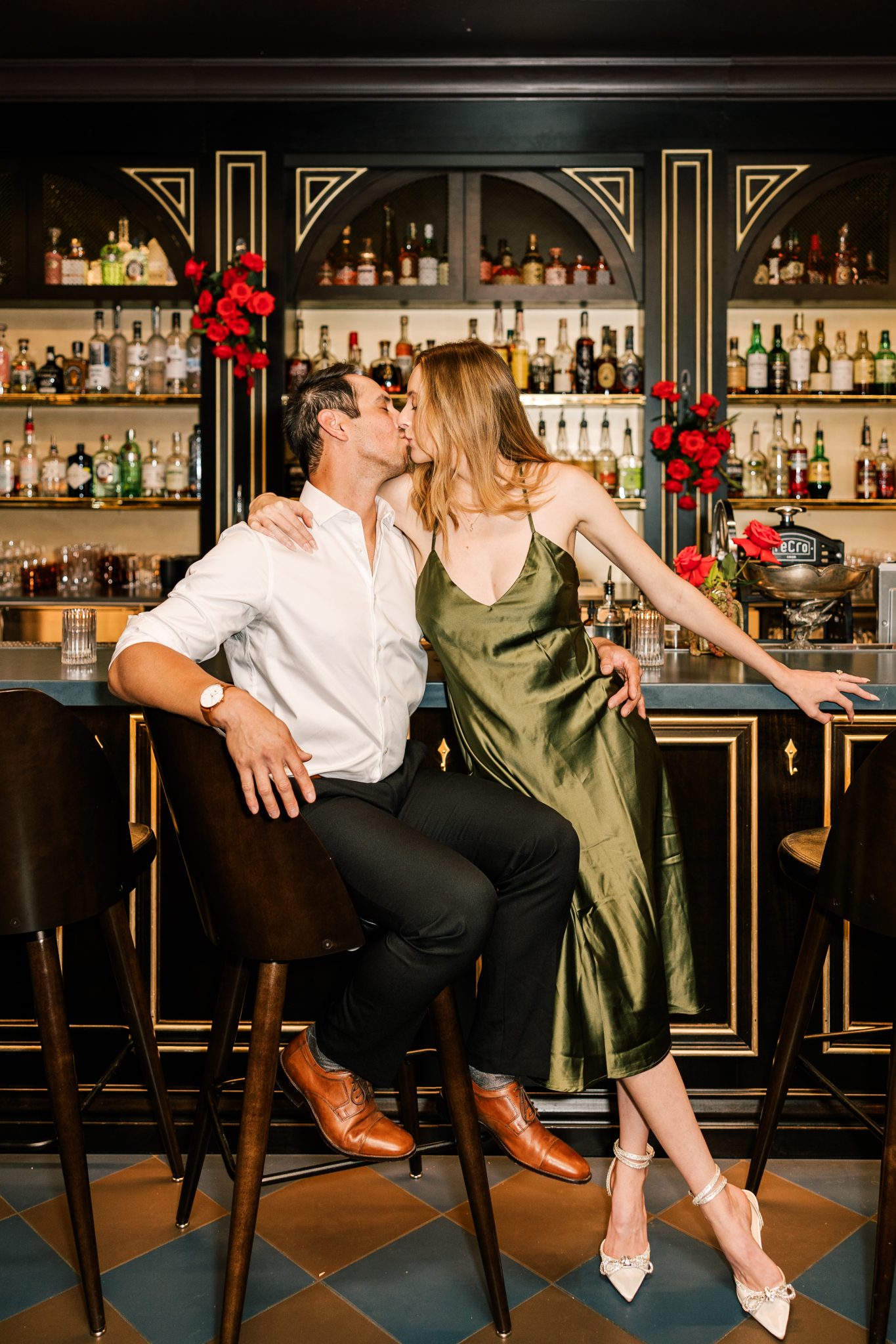 A couple kissing at a beautifully styled bar with classic architecture and red rose accents, embodying the sophisticated vibe of city engagements in Boise.