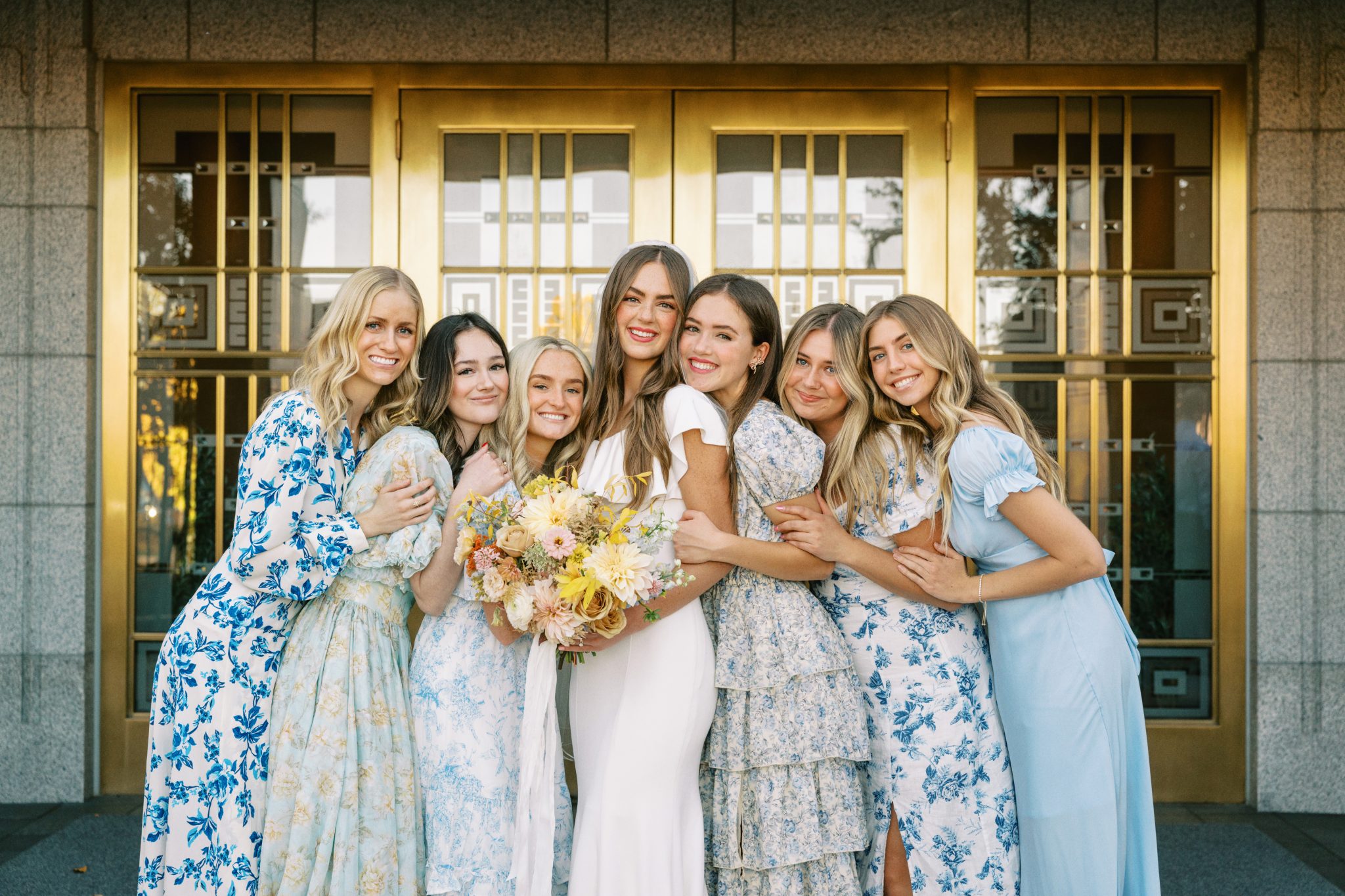 A bride holding a vibrant bouquet featuring white, blush, and peachy flowers with touches of greenery, perfect for a Fall Utah Wedding with Colorful Tones.