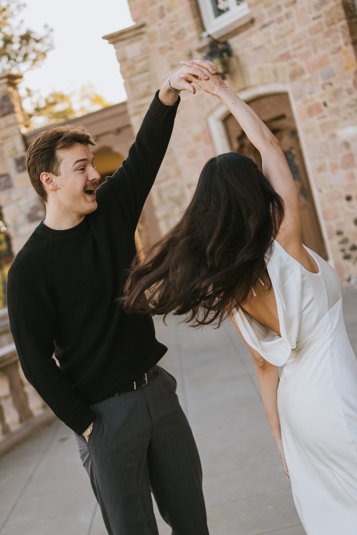 The couple shares a joyful twirl in front of the Highlands Ranch Mansion during their fall engagement session.