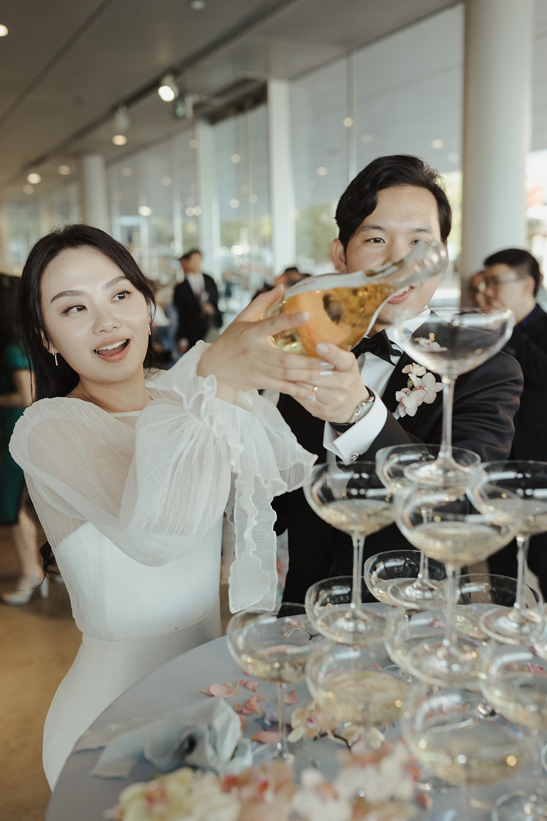 Bride and groom celebrate by pouring a champagne tower during their British Columbia elegant wedding reception.