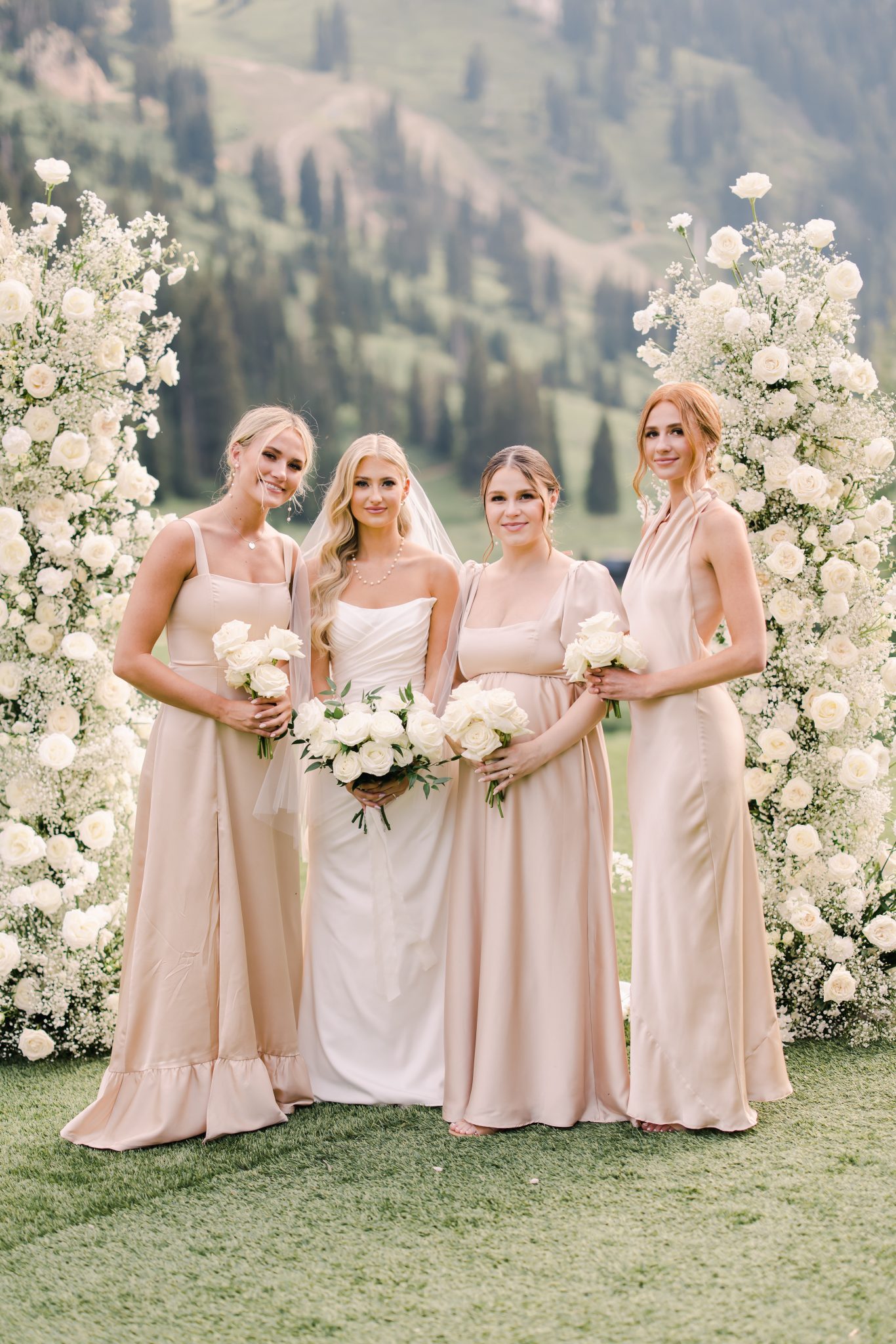 A serene photo of the bride with her bridesmaids in soft blush and cream dresses, set against the lush mountain backdrop of a Snowpine Lodge wedding.