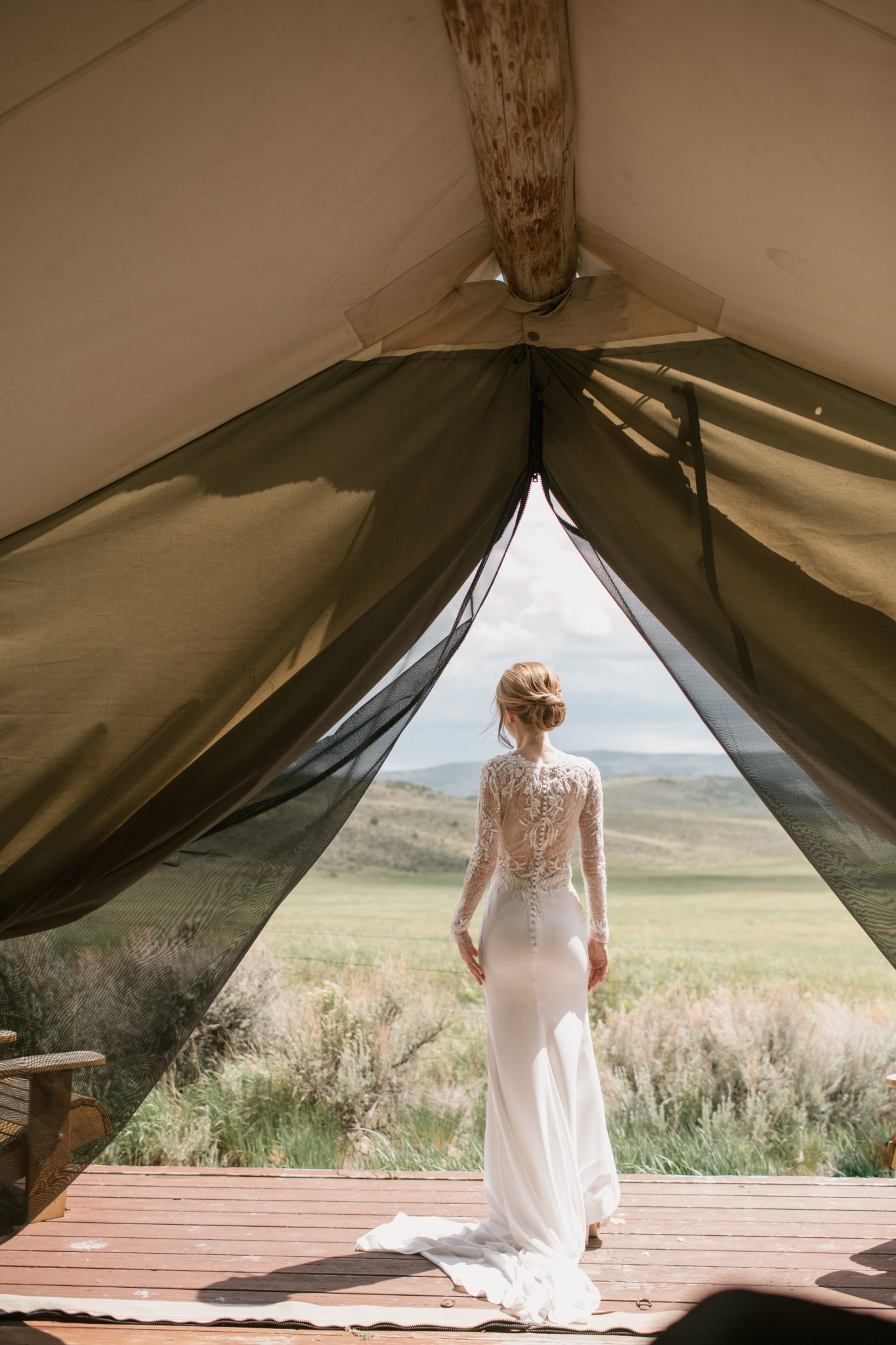 A bride looks out from a glamping tent at the serene mountain scenery during a Four Seasons Resort Vail wedding.