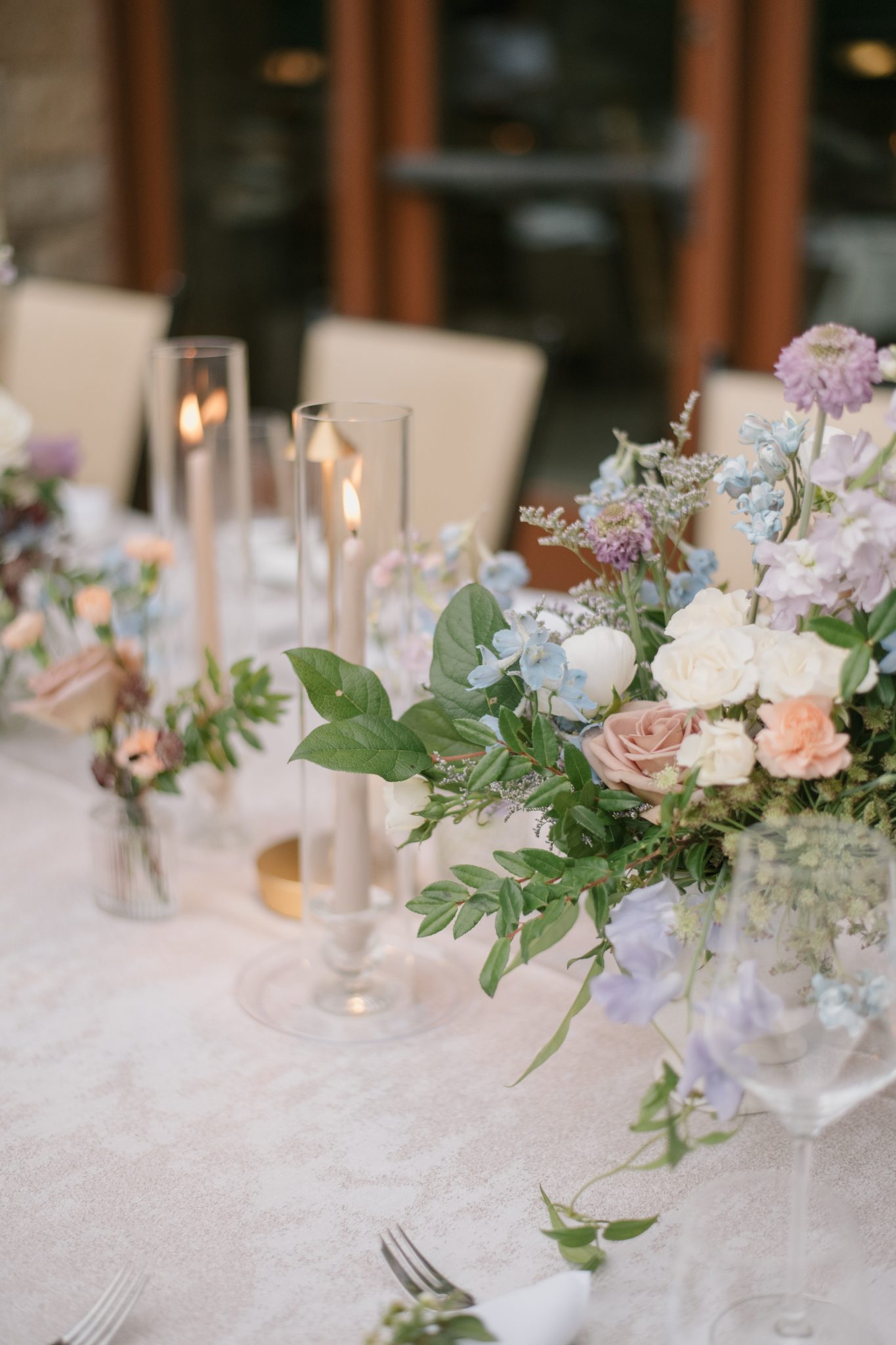 A stunning floral table arrangement featuring pastel tones and taper candles, perfect for a Four Seasons Resort Vail wedding reception.
