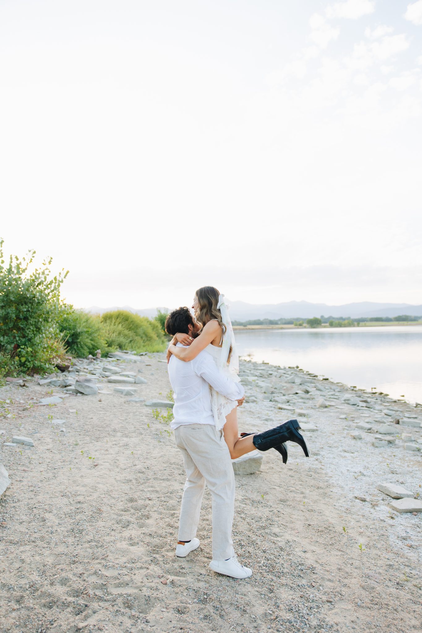 A joyful moment by the water as the couple shares a playful lift during their fall Loveland engagements.