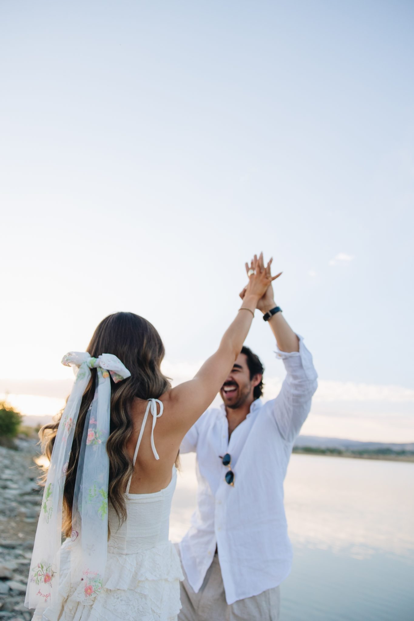 A playful and romantic twirl on the lakeshore with soft light and a beautiful floral bow, highlighting the charm of their fall Loveland engagements.