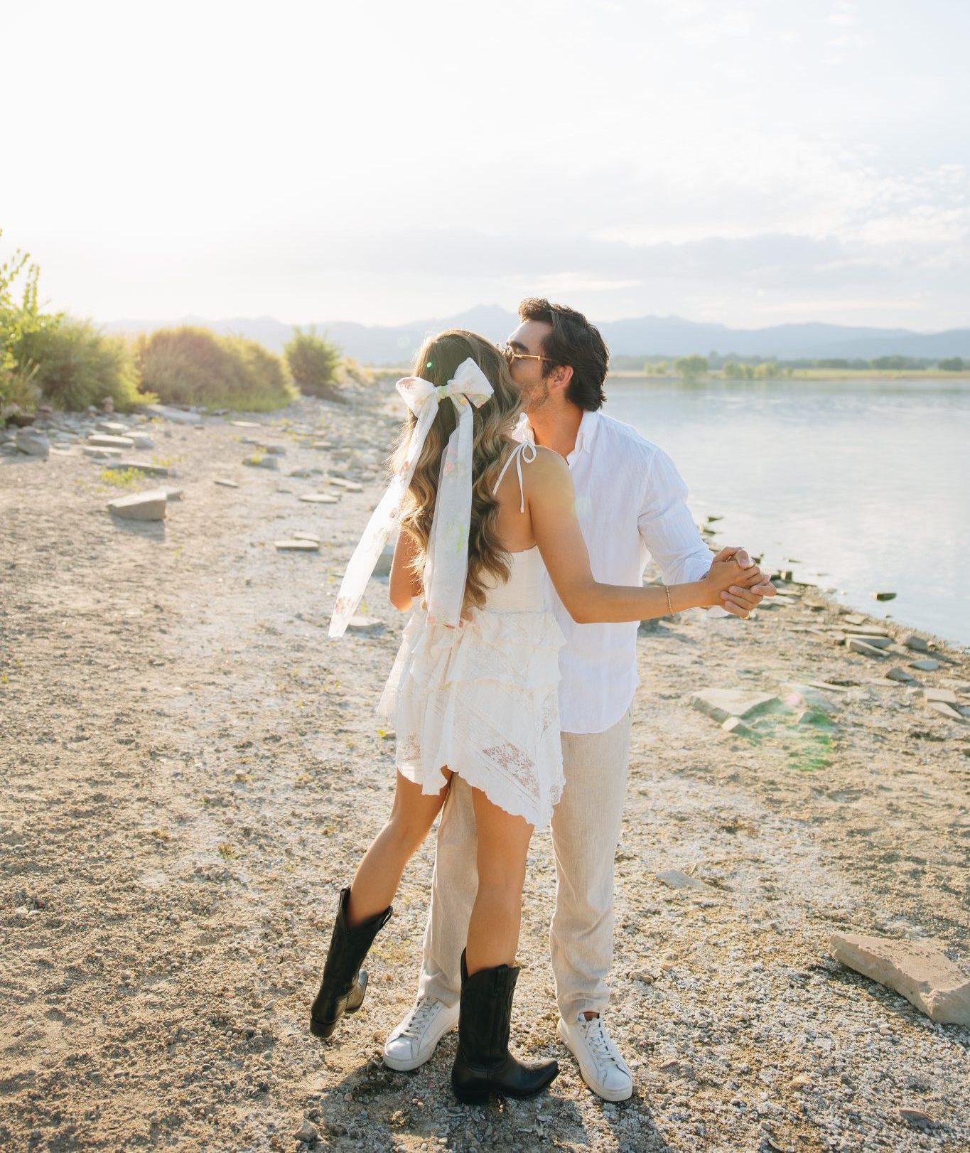 The couple dances along the lakeshore, framed by golden sunlight and serene mountain views during their fall Loveland engagements.