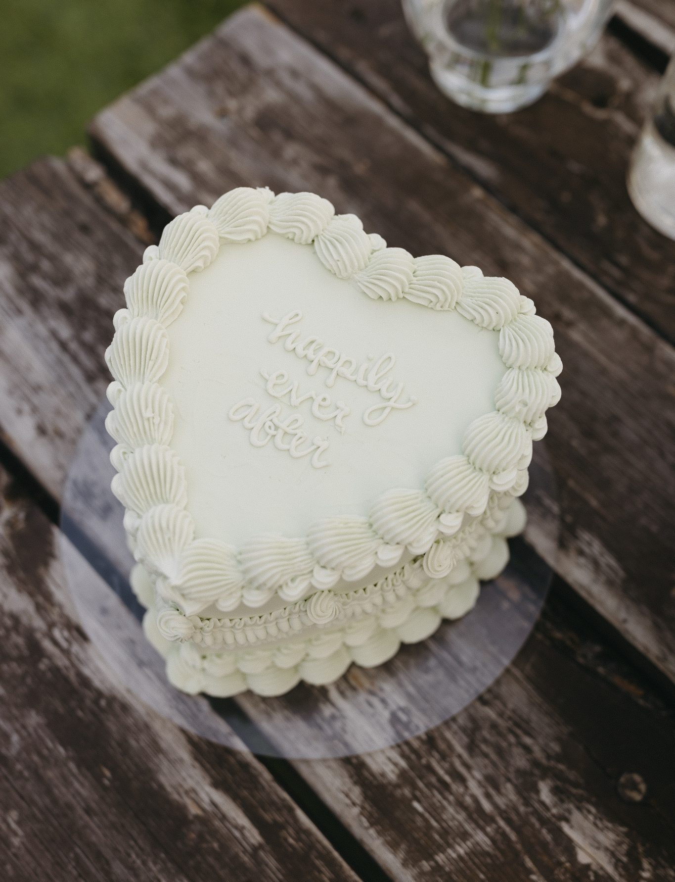 A close-up of a heart-shaped white wedding cake with "happily ever after" icing detail, adding charm to The Gathered weddings.