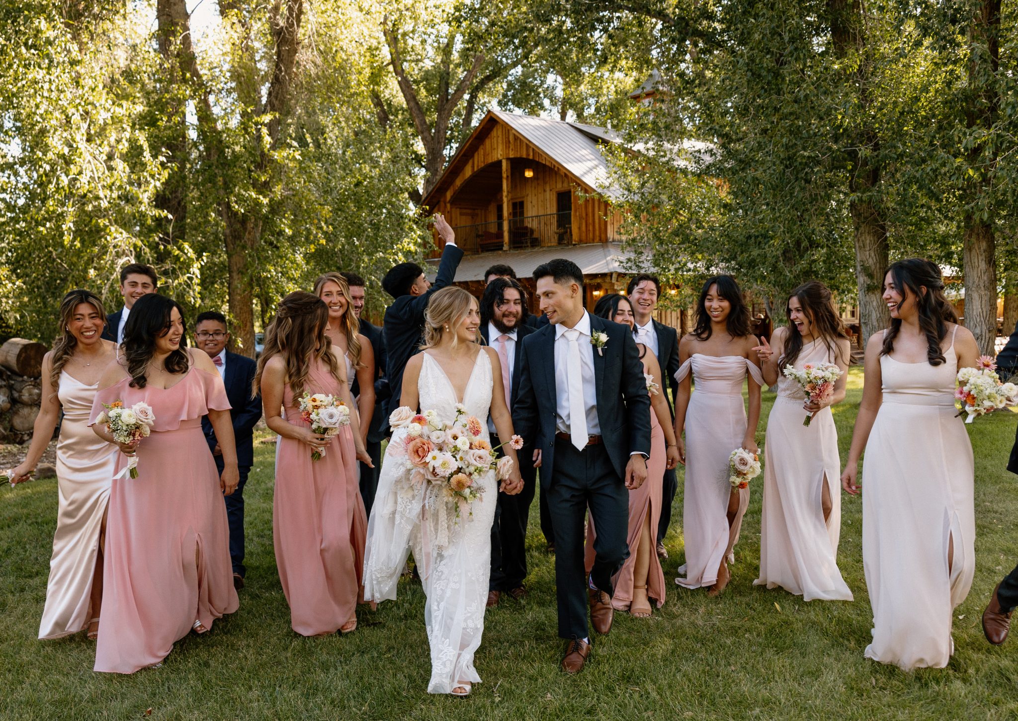 The bridal party celebrates with the newlyweds at a Western Durango summer wedding, featuring blush-toned dresses and joyful smiles.