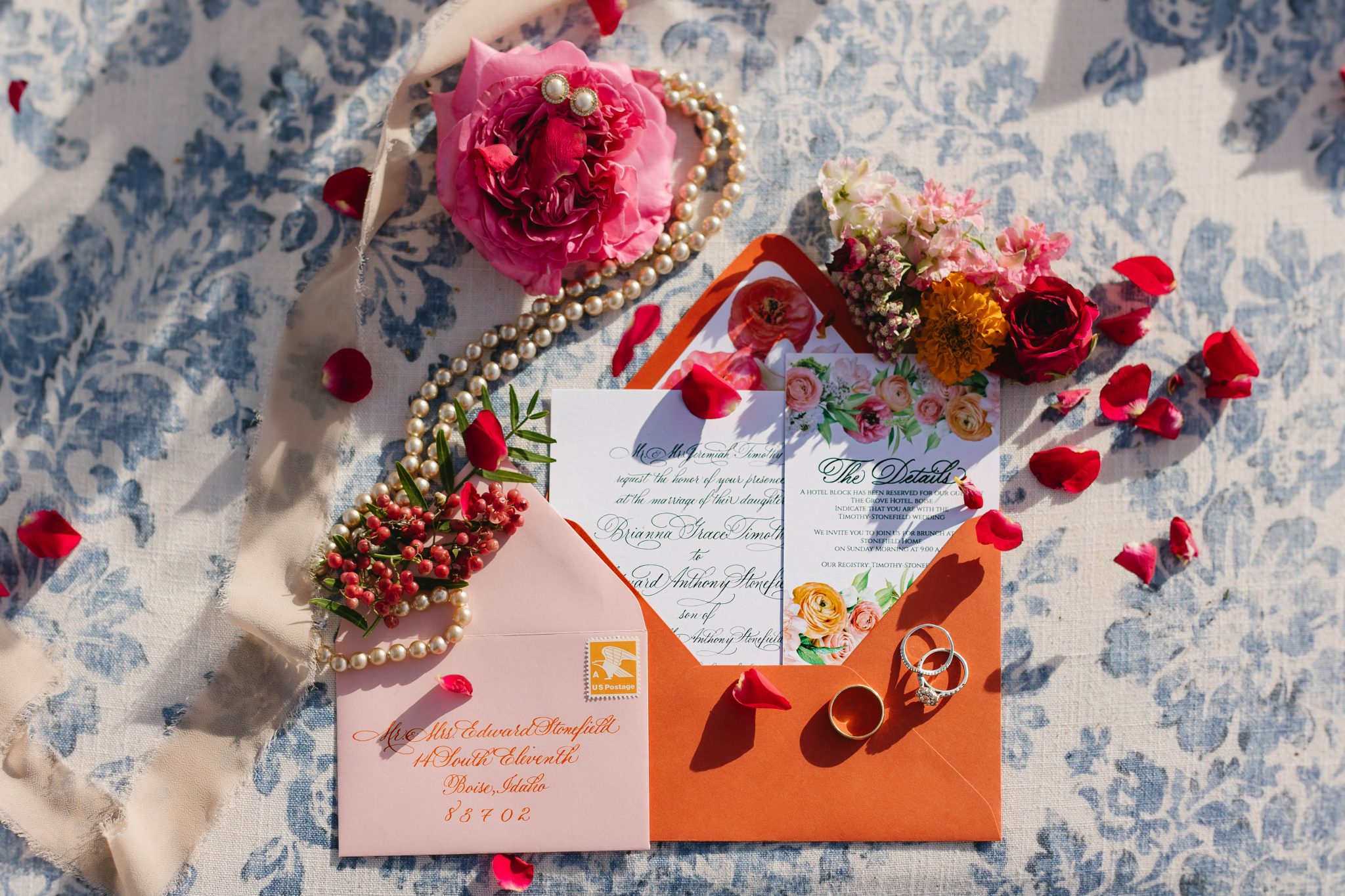 A vibrant tablescape featuring orange and pink wedding flowers, accented with glassware and natural textures.