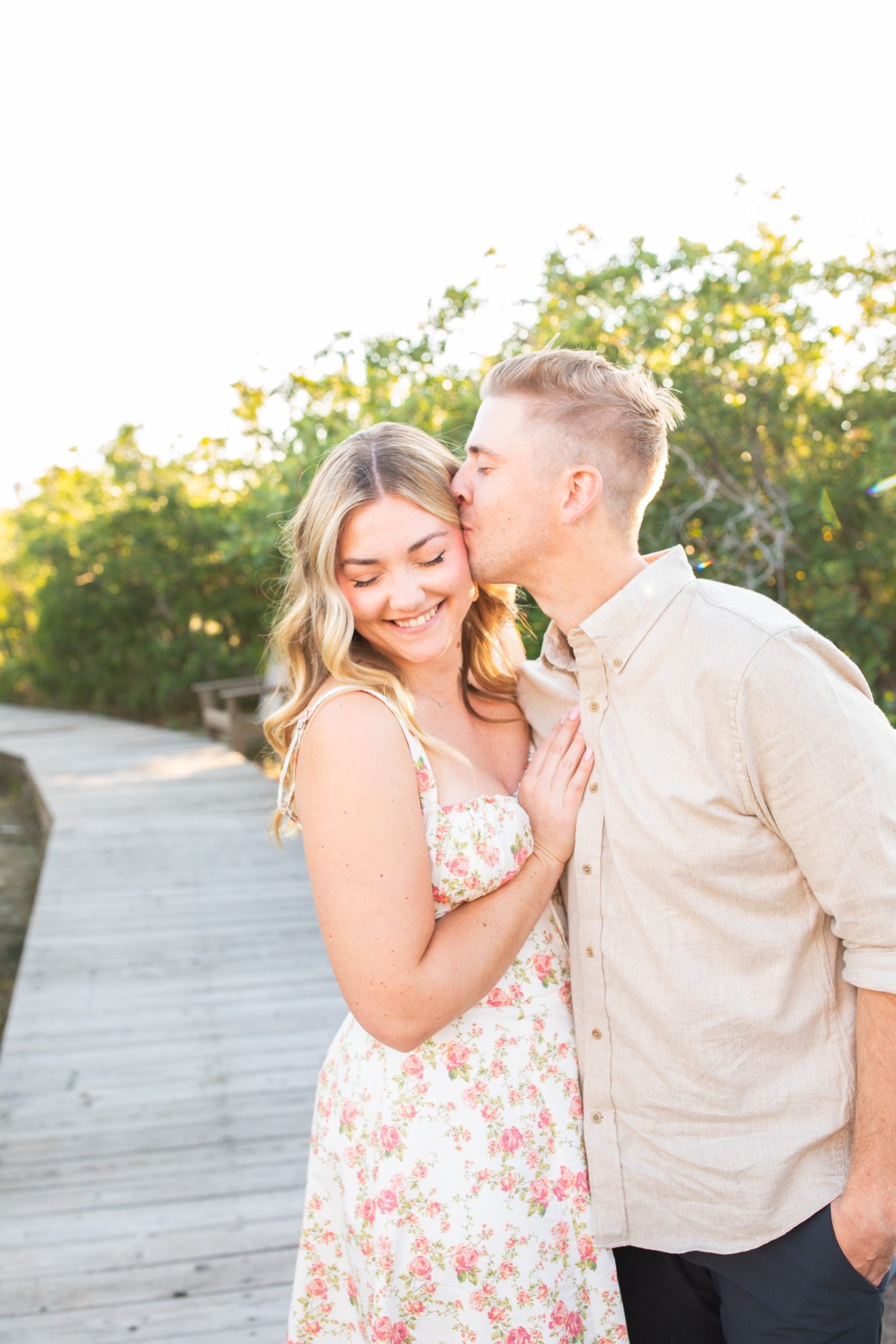 The couple shares an intimate moment after their Utah wedding proposal, standing together on a wooden pathway in the serene countryside.