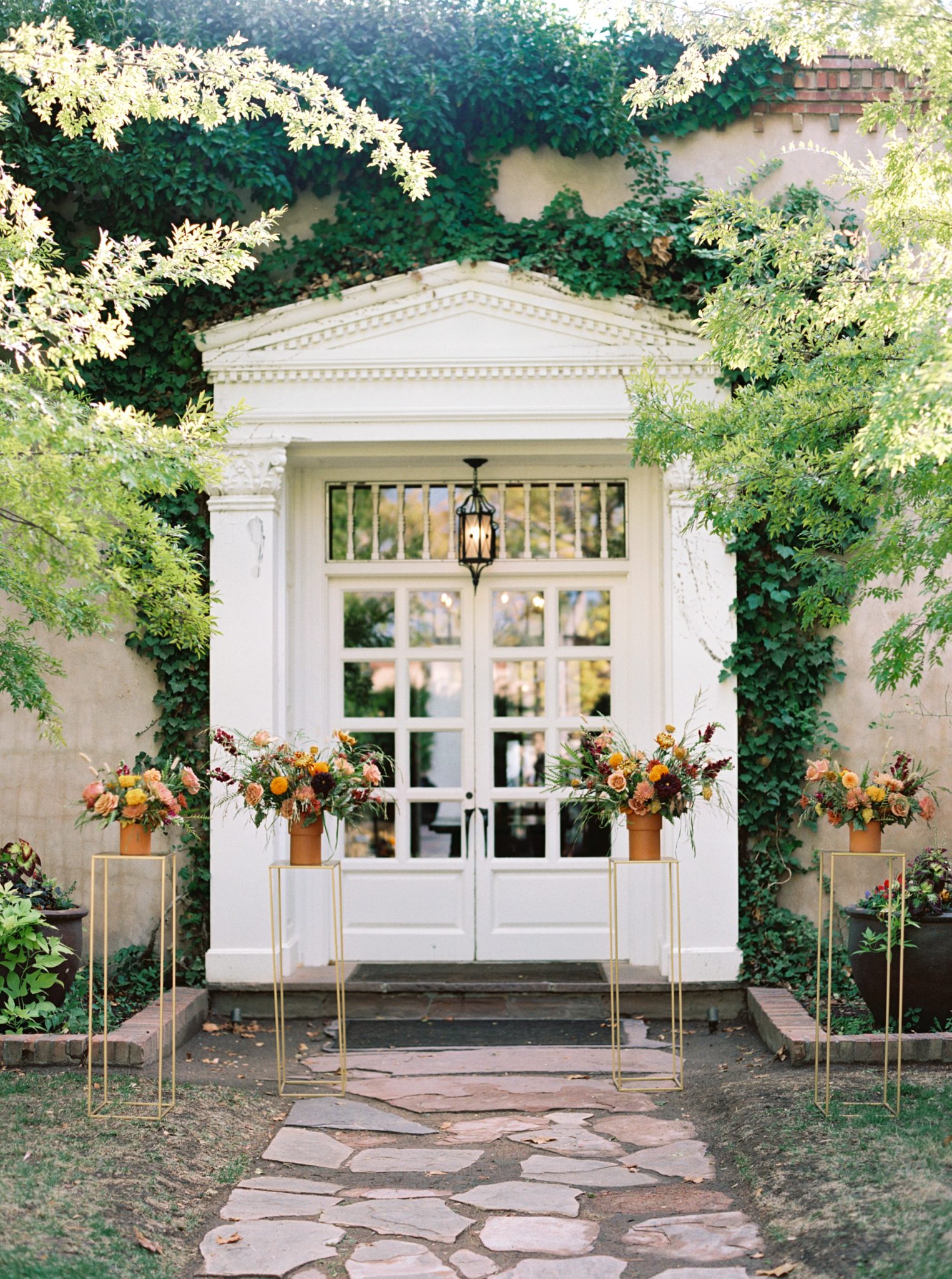 A beautiful ceremony setup with vibrant floral arrangements against an ivy-covered wall at a Los Poblanos New Mexico wedding.