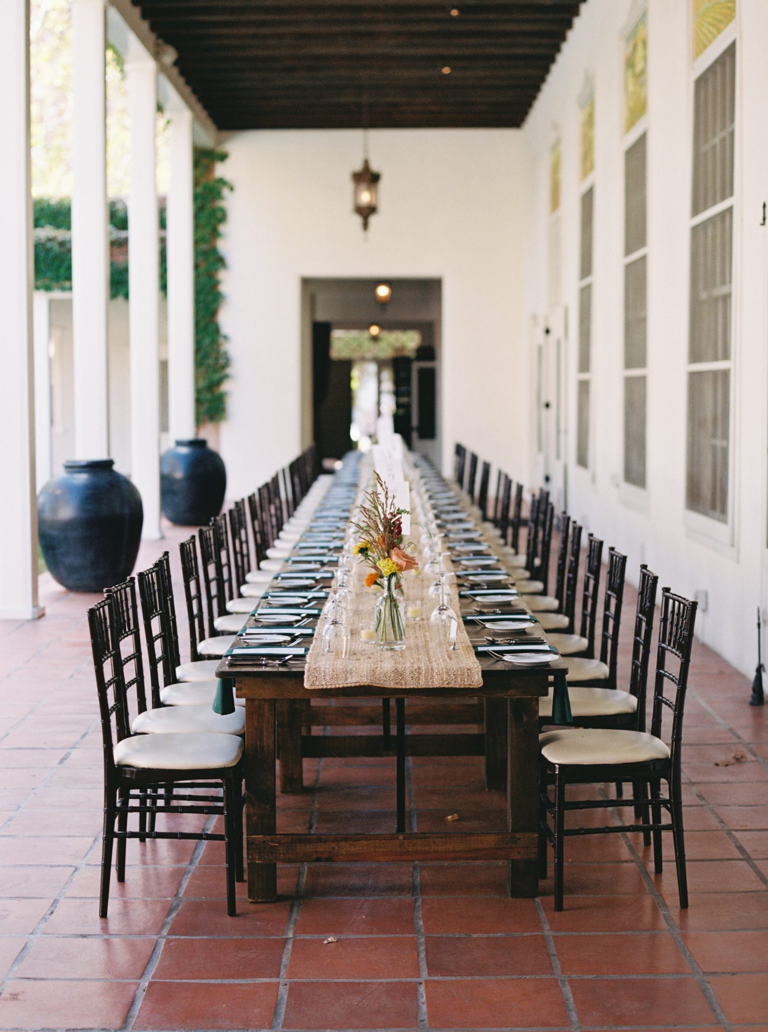 A long banquet table styled with minimalistic tableware and delicate floral accents at a Los Poblanos New Mexico wedding reception.