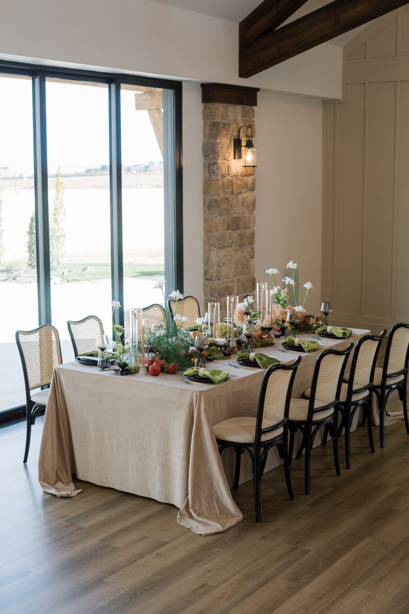 A romantic editorial tablescape with neutral linens, vibrant florals, and modern black and cane chairs.