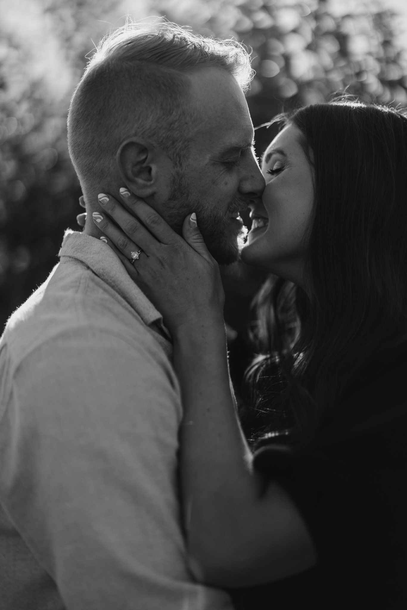 A black-and-white close-up of a couple sharing an intimate moment, focusing on their smiles and an engagement ring, perfect for Montana engagement photos.