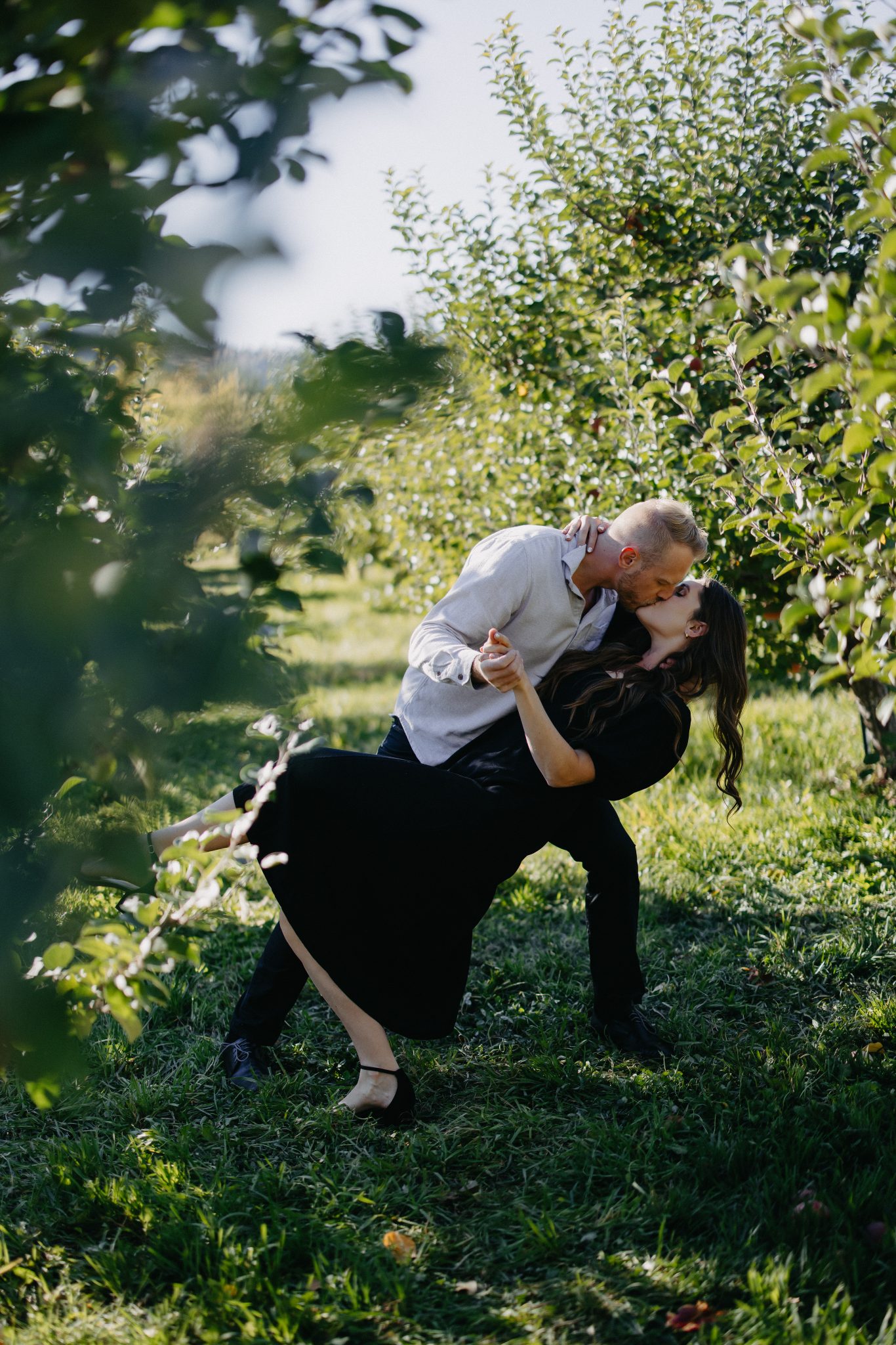 A playful dip kiss between a couple in an apple orchard, showcasing the love and joy of Montana engagement photos.