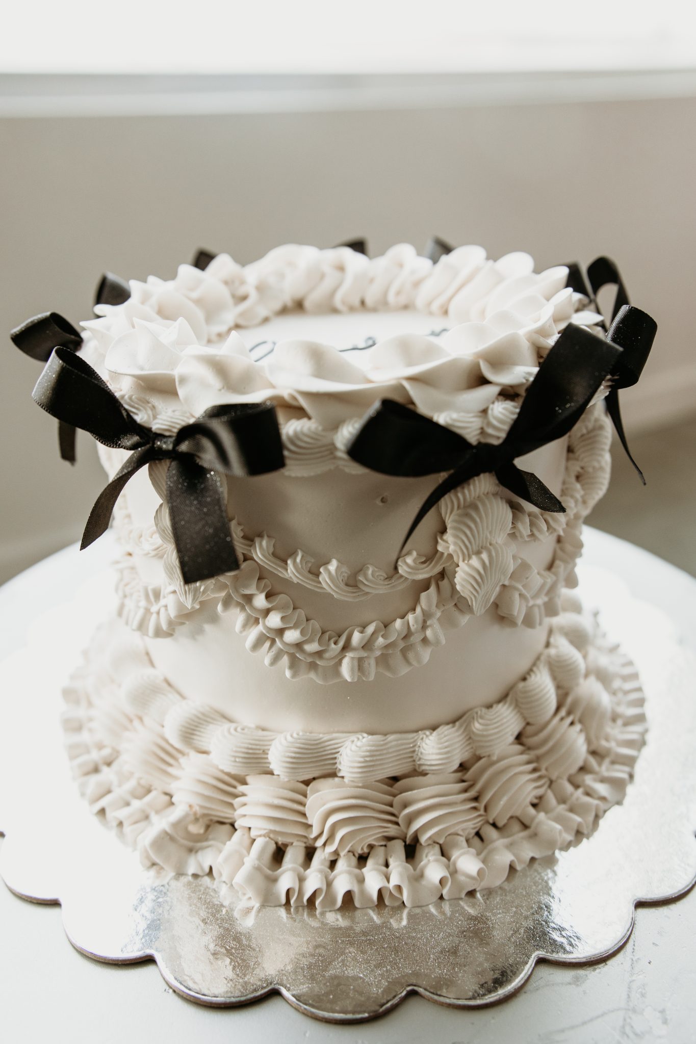 Vintage-inspired white wedding cake with black ribbon details and intricate piping, styled for a romantic Valentine's Day Editorial.
