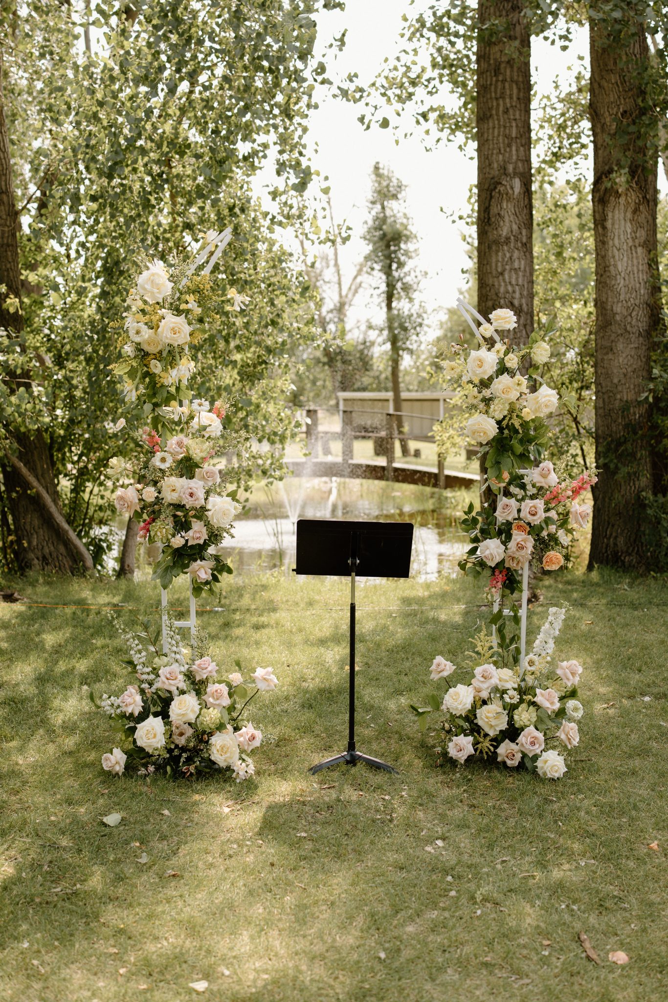 Romantic floral arch arrangement under trees for an Outdoor Alberta wedding ceremony.