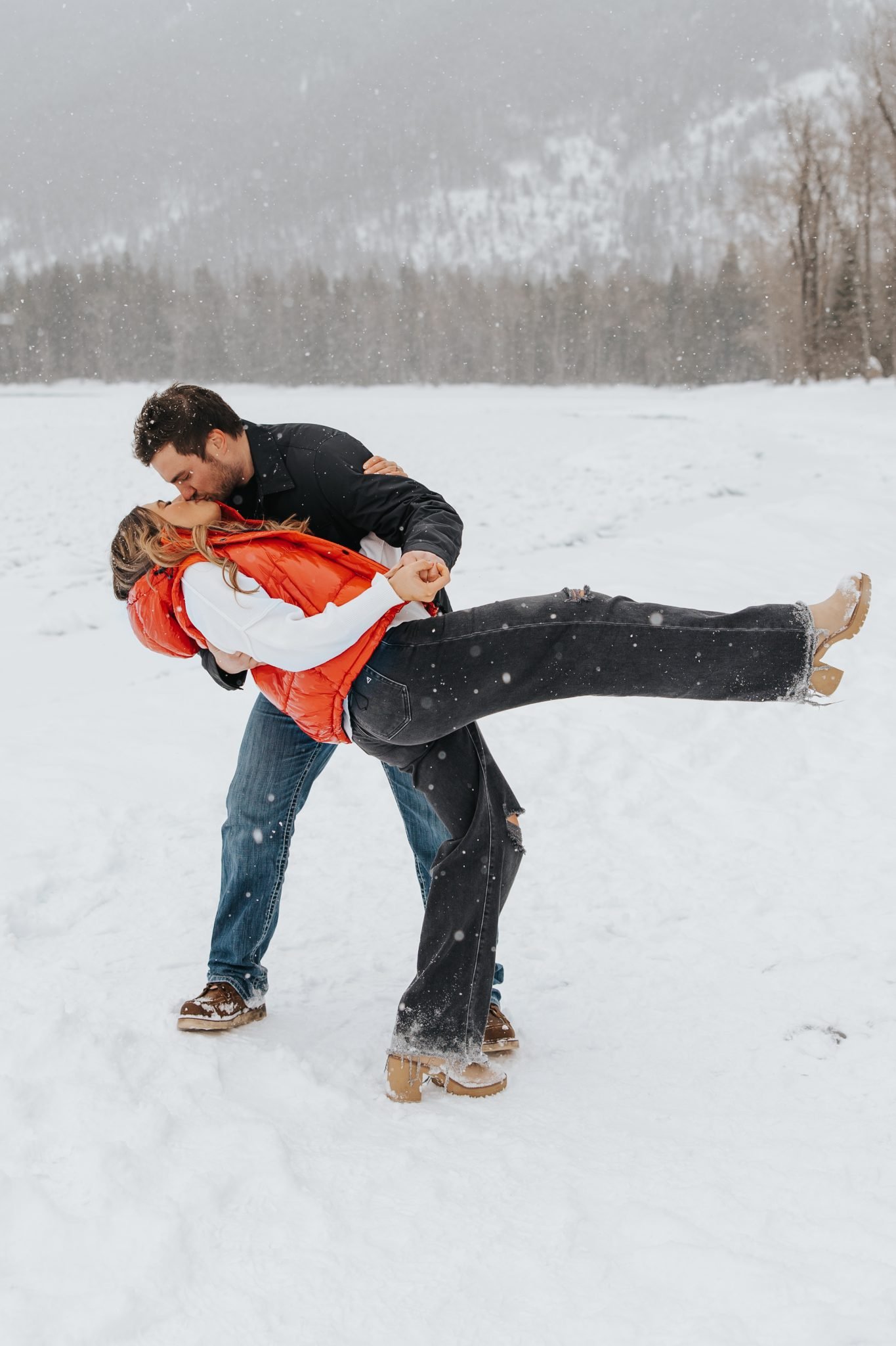 Romantic dip kiss in the snow – A couple embraces in a breathtaking snowy Montana scene, as the groom dips his bride for a passionate kiss, embodying the love of snowy montana engagements rocky mountain bride.