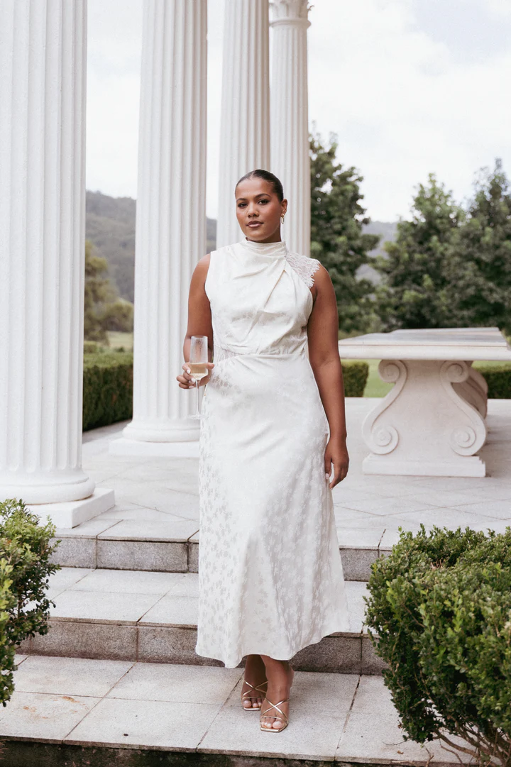 A sophisticated white lace halter-neck maxi dress, perfect for a bridal gown alternative or wedding reception dress.