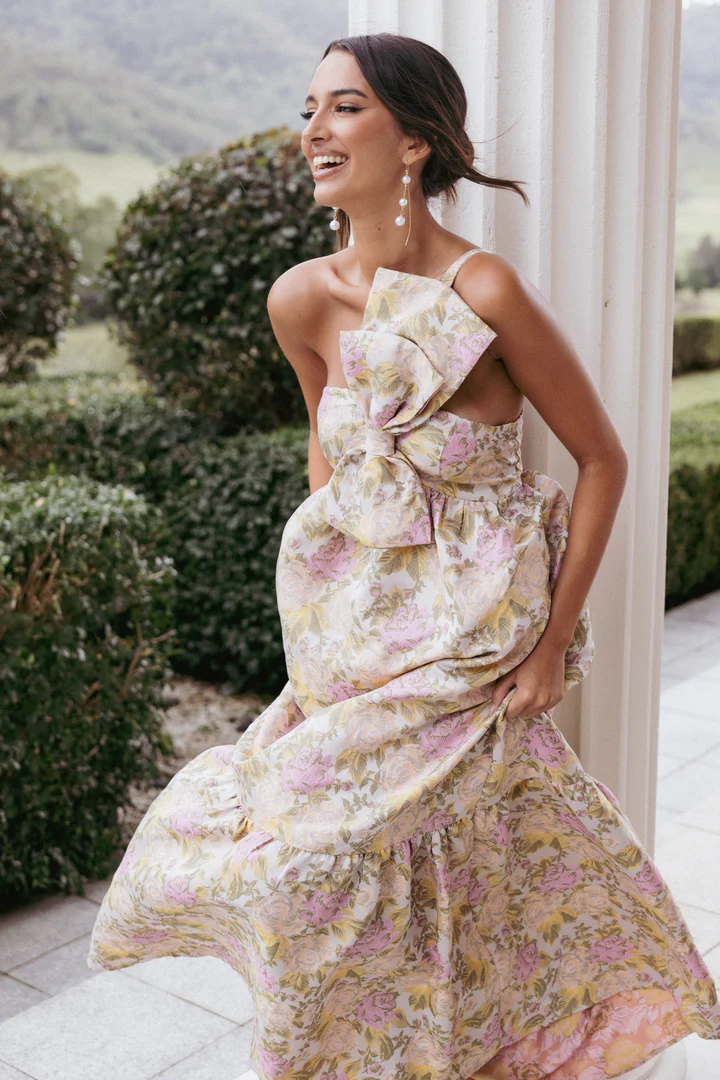 A romantic floral maxi dress with a bow-front detail, perfect for a wedding guest or rehearsal dinner look.