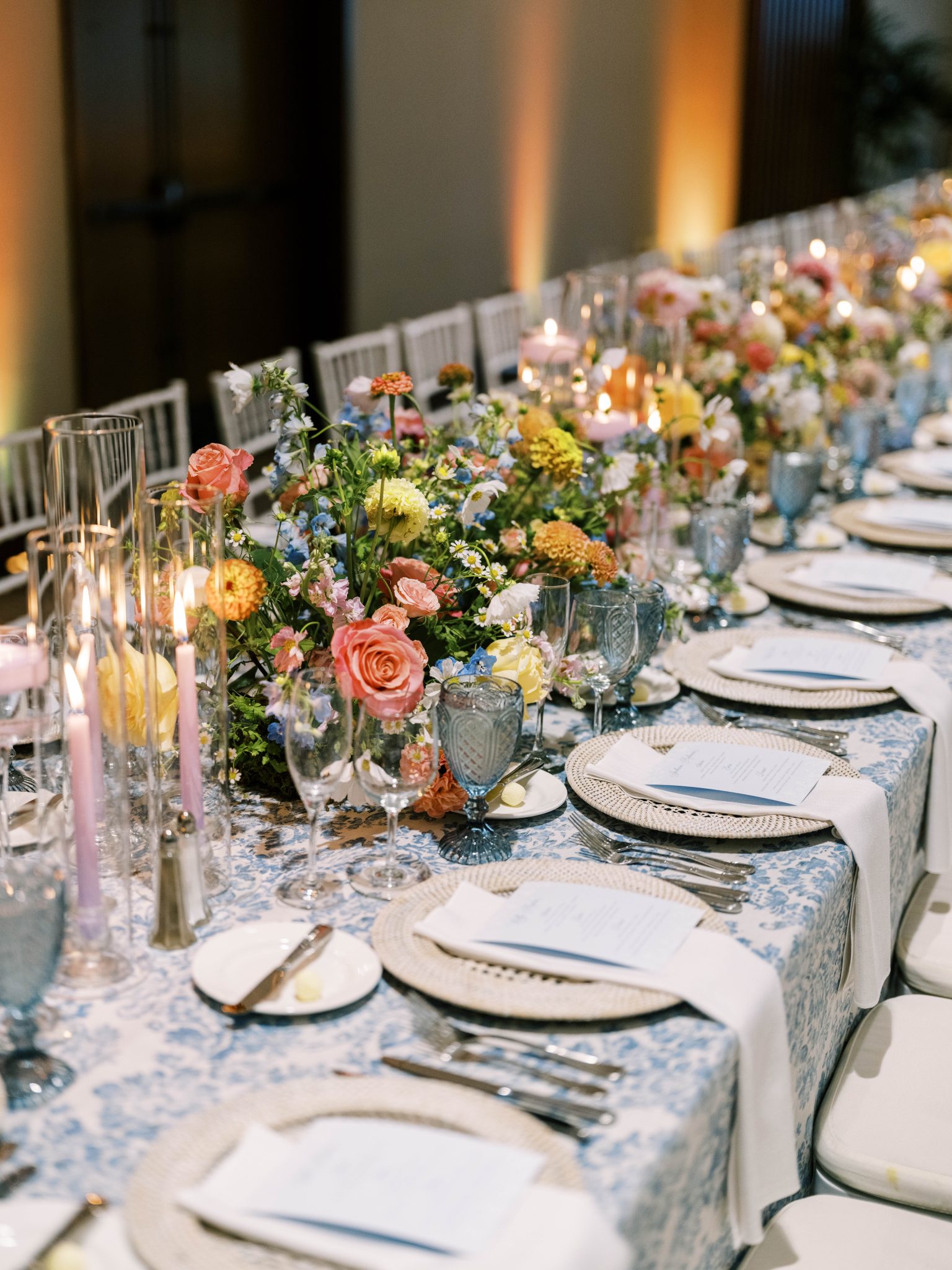 A beautifully styled reception table with colorful floral arrangements, candlelit ambiance, and elegant blue and white table settings at an Elegant Summer Wedding in Snowmass Colorado