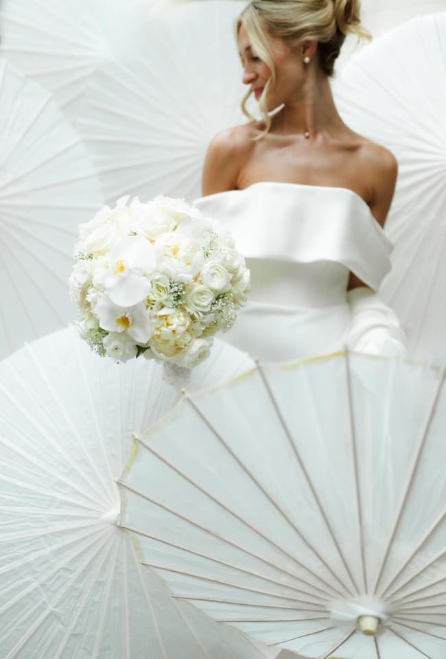 bride surrounded by white umbrellas holding bouquet