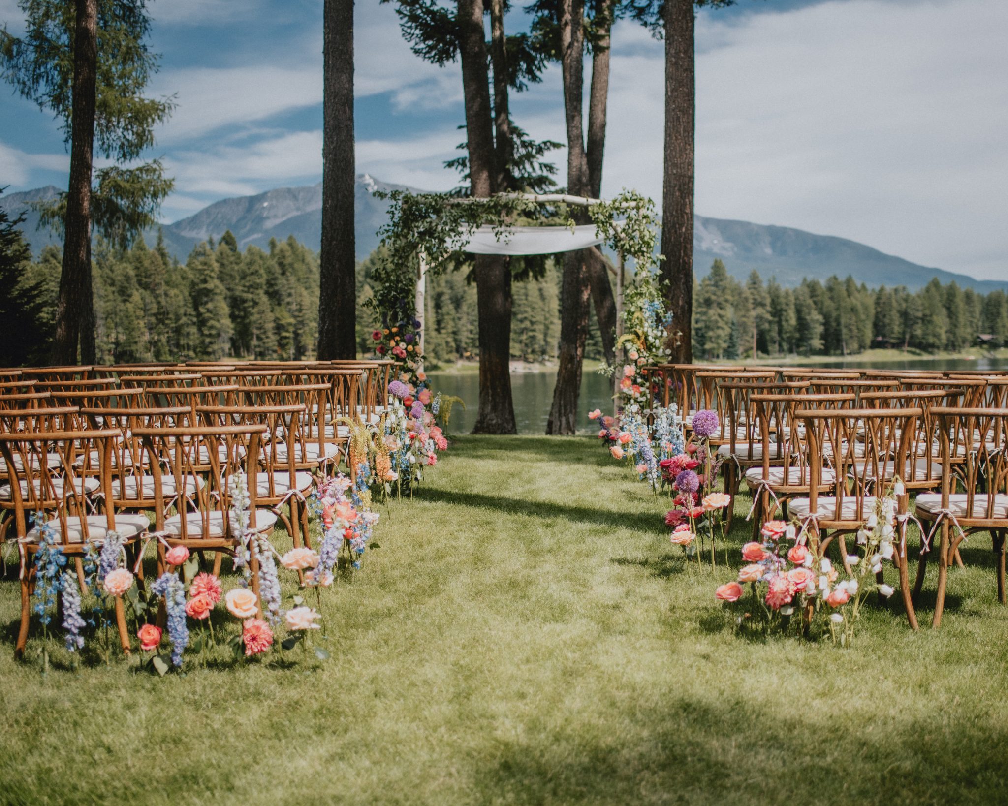 A breathtaking outdoor reception in the Montana mountains featuring white table linens, wildflower-inspired centerpieces, and an intimate yet lively ambiance for a Vibrant Montana outside wedding.