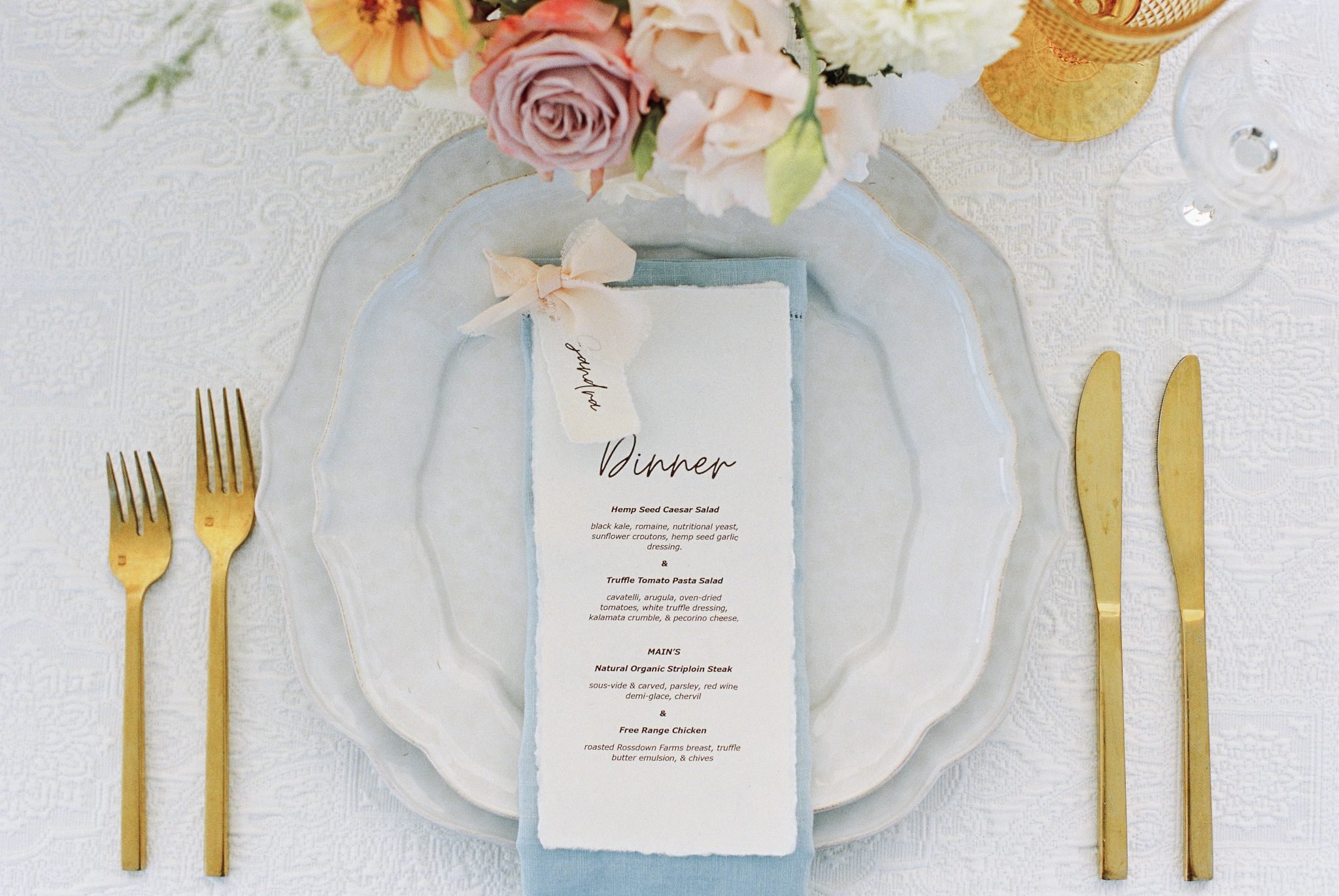 Elegant table setting featuring pastel florals, gold accents, and soft blue details at a Sunshine CC Bloom Flower Farm summer wedding.