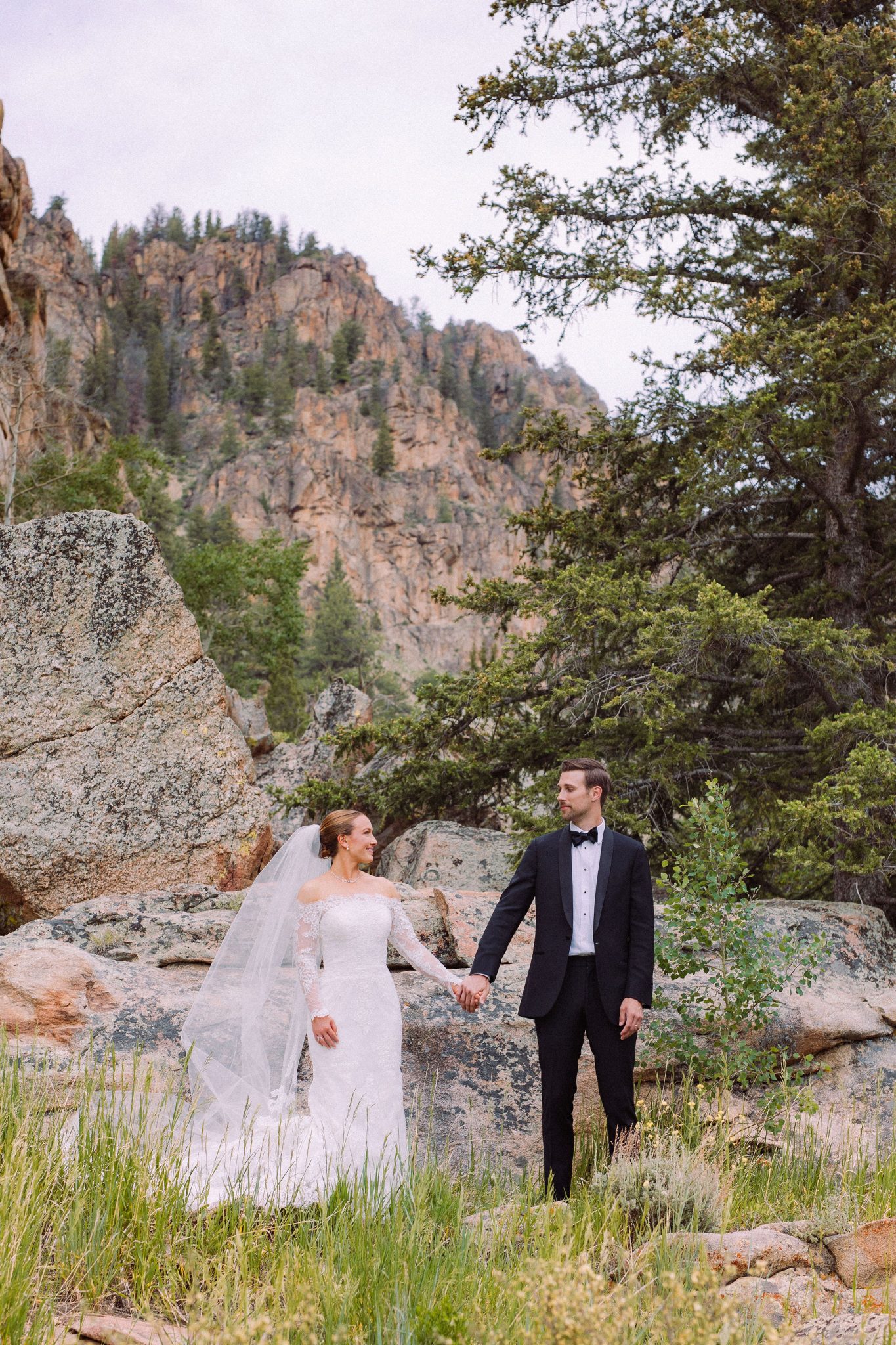 A bride and groom stand among the rugged beauty of the Colorado mountains, capturing the essence of a Colorado wedding mountain wedding Rocky Mountain Bride.