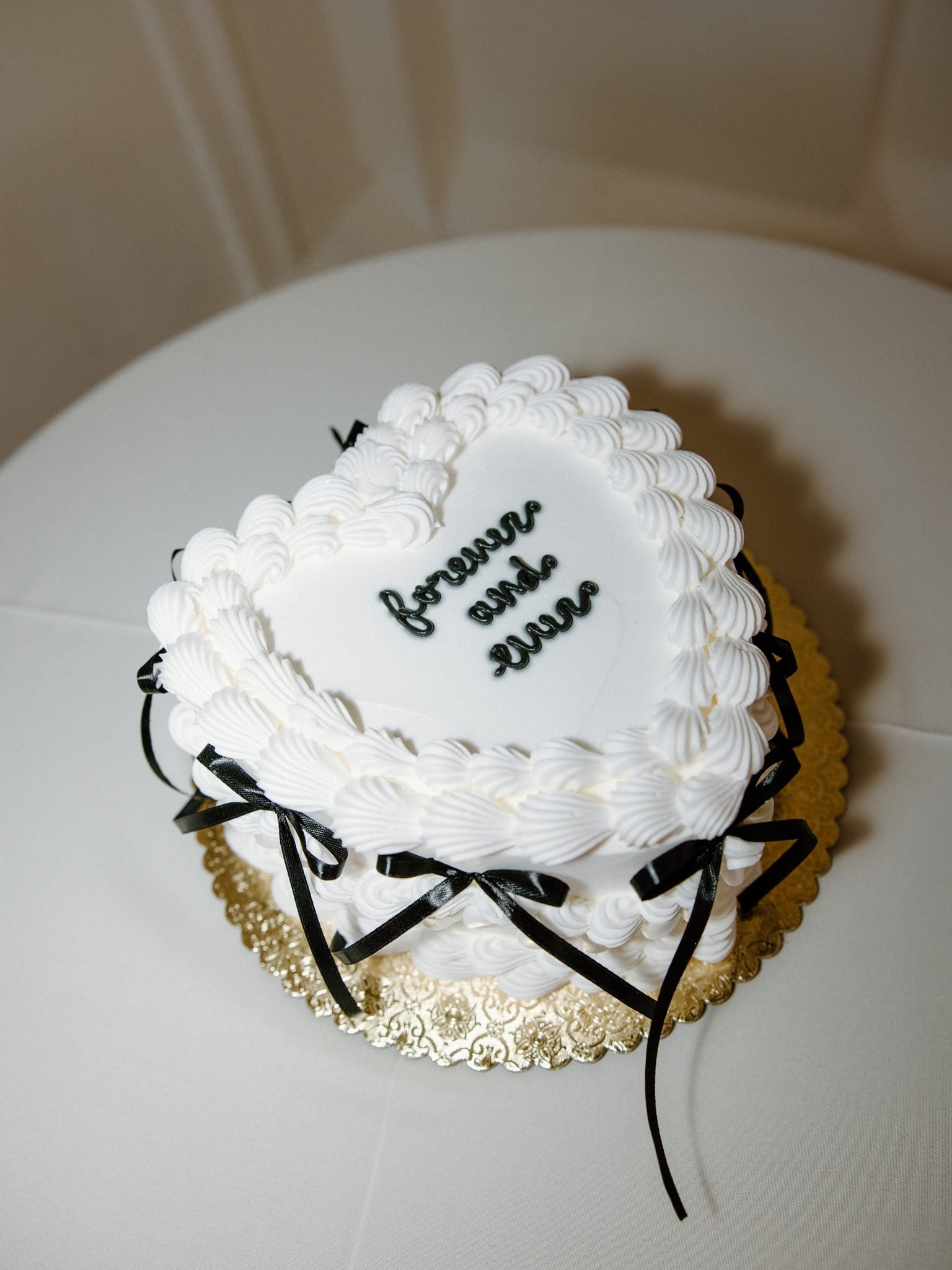 A vintage-inspired heart-shaped wedding cake with black ribbon details at commercial club salt lake city utah.